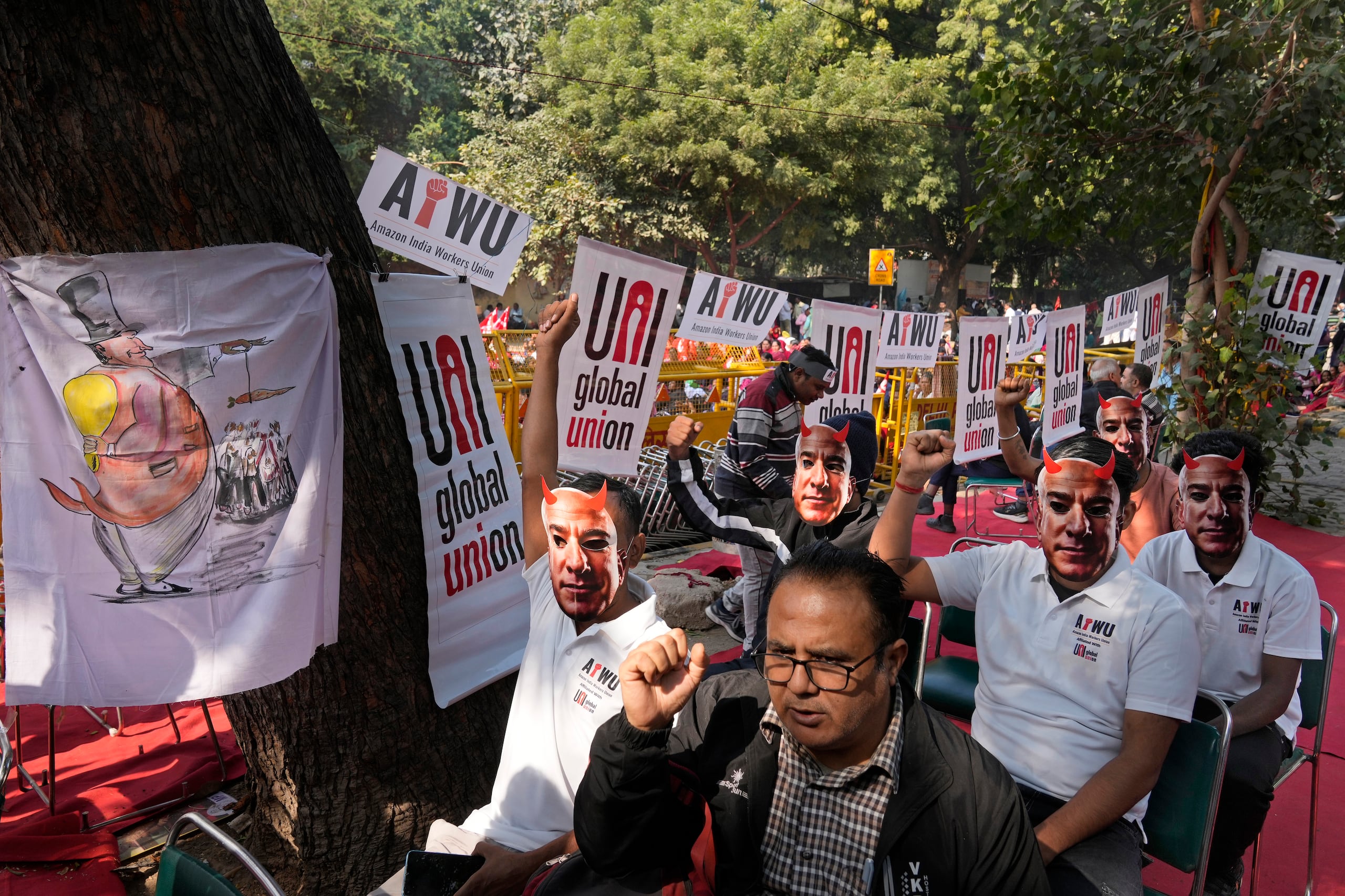 Participantes de una protesta portan máscaras con la imagen del dueño de Amazon, Jeff Bezos, al tiempo que trabajadores de almacén y conductores de entrega se congregaron en la capital, Nueva Delhi, India, para exigir mejores salarios y condiciones laborales, el viernes 29 de noviembre de 2024. (AP Foto/Manish Swarup)
