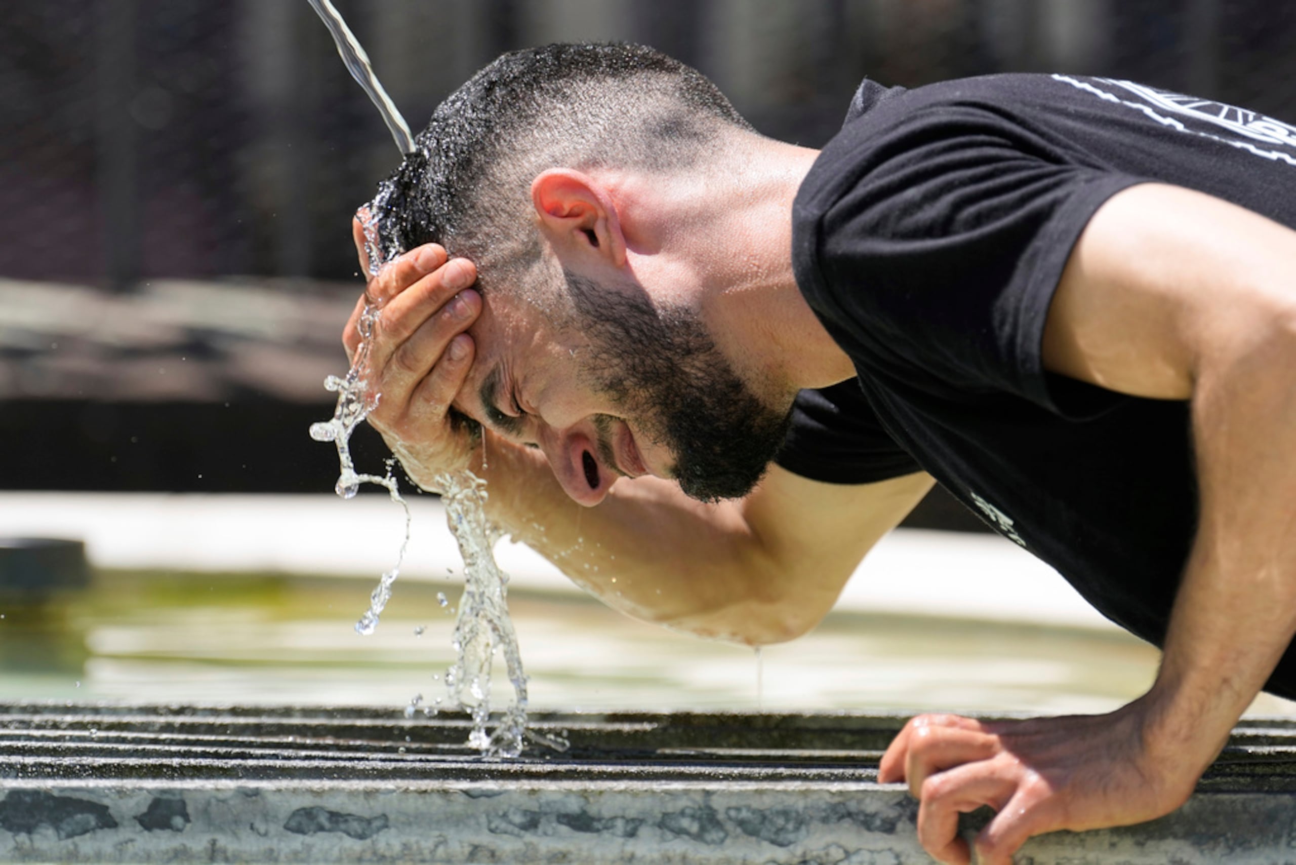 Mientras, un trabajador se refresca en una fuente en la ciudad de Basel, Suiza.