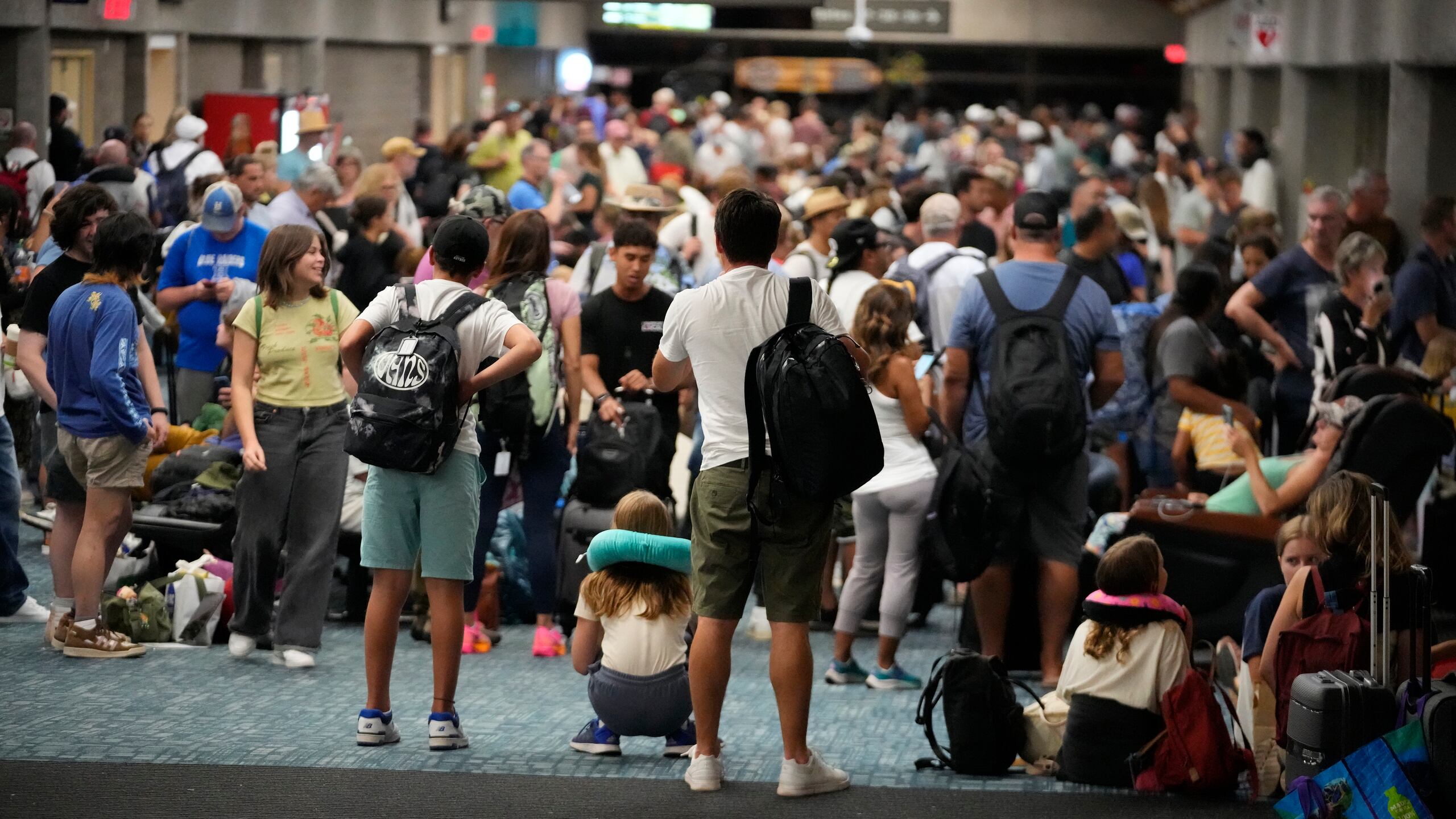 People gather at the Kahului Airport while waiting for flights Wednesday, Aug. 9, 2023, in Kahului, Hawaii. Several thousand Hawaii residents raced to escape homes on Maui as the Lahaina fire swept across the island, killing multiple people and burning parts of a centuries-old town. (AP Photo/Rick Bowmer)