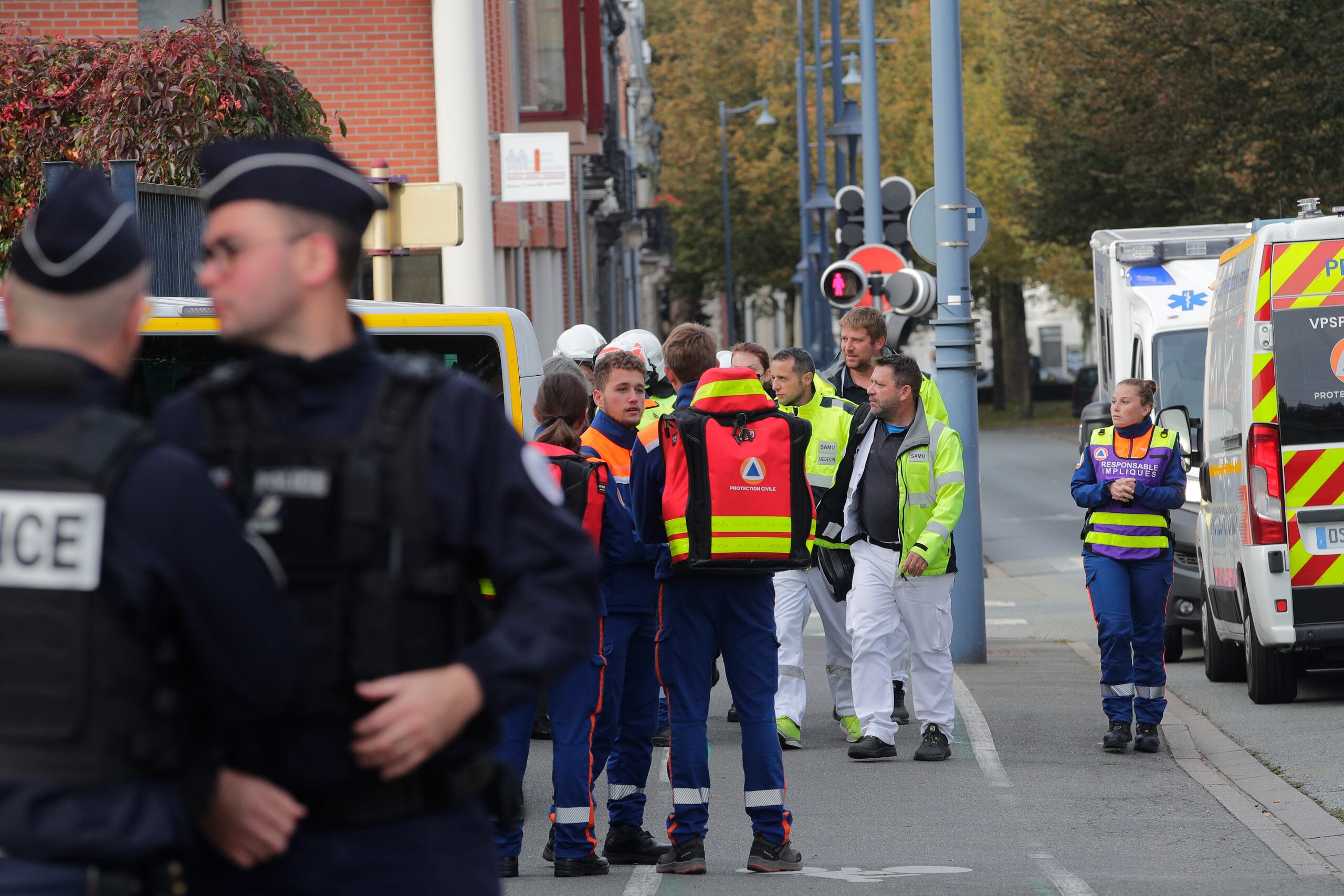Police officers and rescue workers wait near the Gambetta high school during a bomb alert Monday, Oct. 16, 2023 in Arras, northern France. French authorities say the high school where a teacher was fatally stabbed in an attack last week has been evacuated over a bomb alert, as France's President cut short travel plans abroad to host a security meeting Monday.(AP Photo/Michel Spingler)