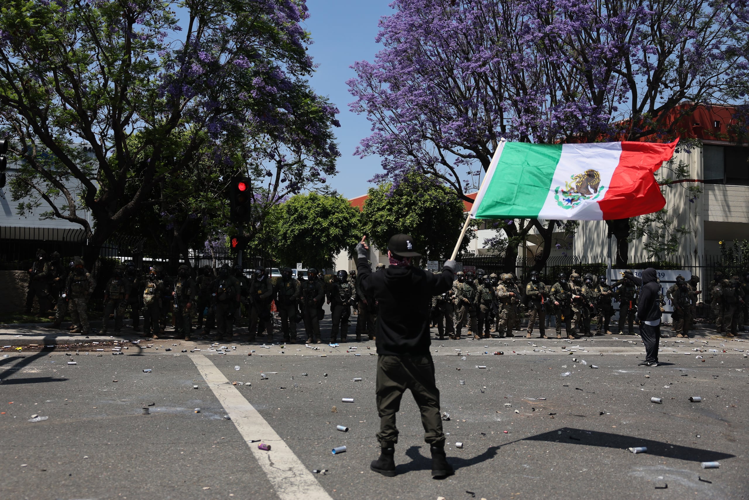 Un manifestante fue captado este sábado, 7 de junio, al sostener una bandera mexicana durante un enfrentamiento con agentes federales después de que el Servicio de Inmigración y Control de Aduanas (ICE) realizara una redada contra presuntos inmigrantes indocumentados, en Paramount (California, EE.UU.). (EFE/Allison )