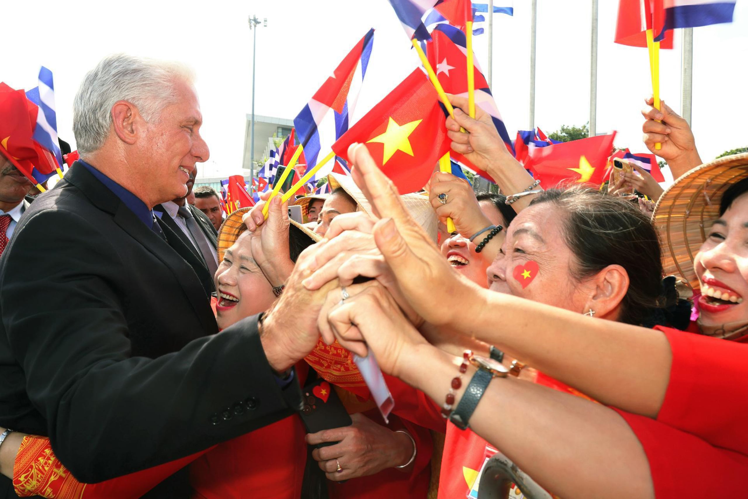 Fotografía cedida este domingo por la Presidencia de Cuba del mandatario Miguel Díaz-Canel (i), saludando a simpatizantes vietnamitas a su llegada a Hanoi (Vietnam).