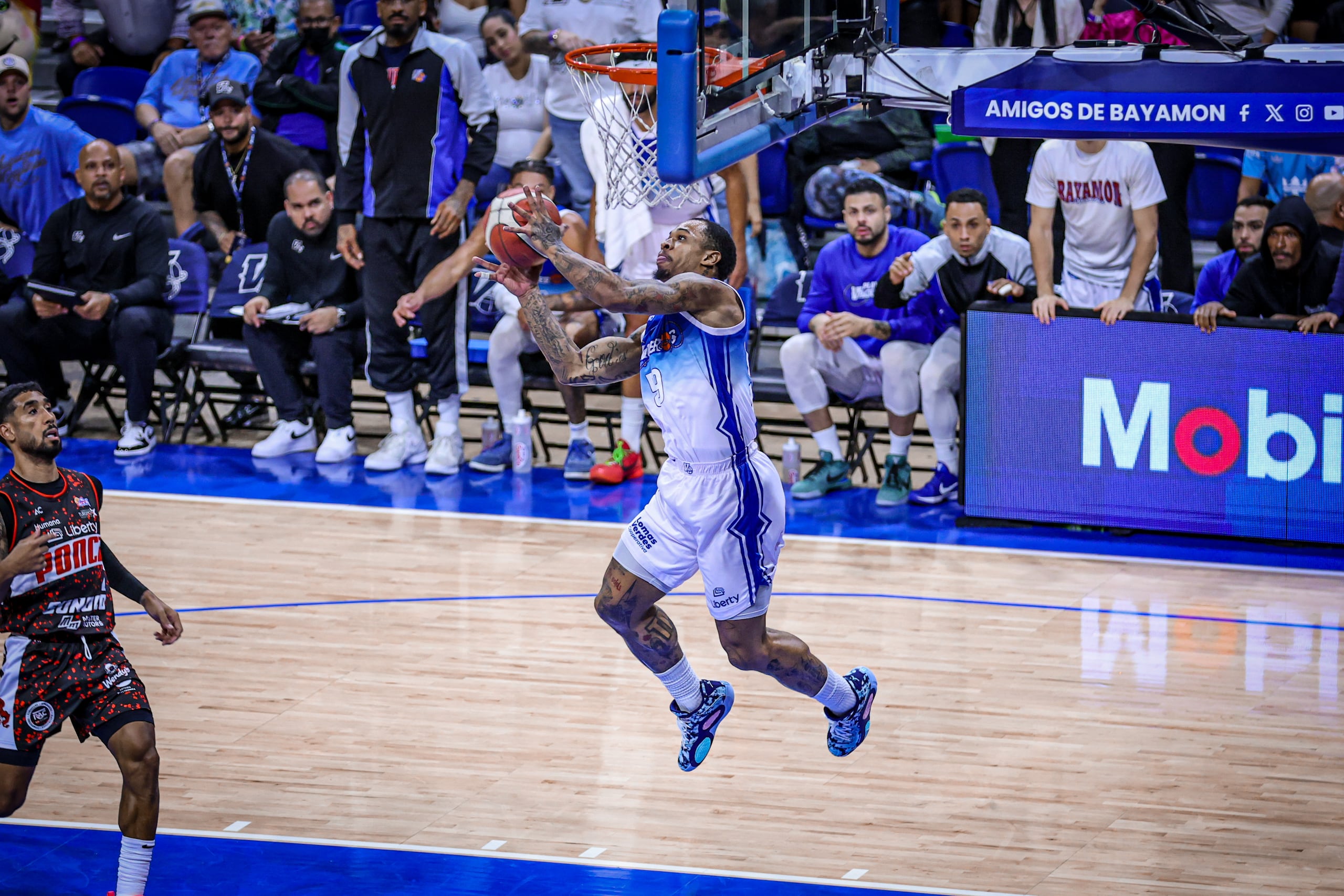 Rayjon Tucker, refuerzo de los Vaqueros de Bayamón, donquea el balón tras un puente aéreo de Gary Browne en el tercer juego de la final del BSN contra los Leones de Ponce.