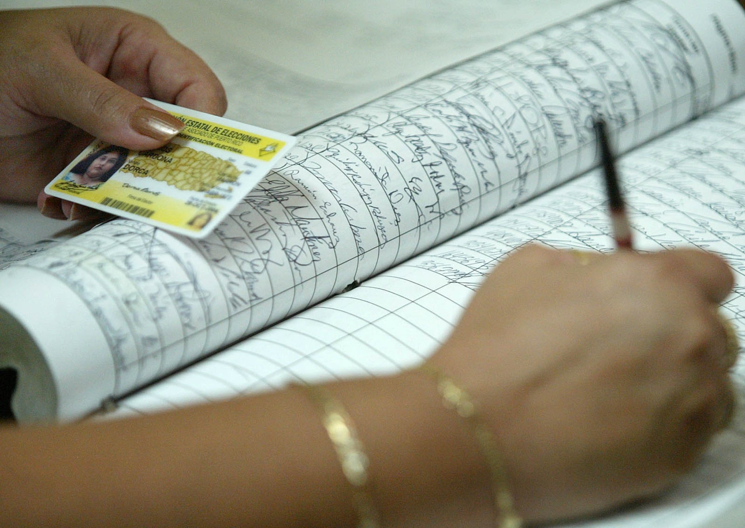 UNA EMPLEADA DE LA CEE ANOTA EL NUMERO DE LA UNA NUEVA TARJETA ELECTORAL.