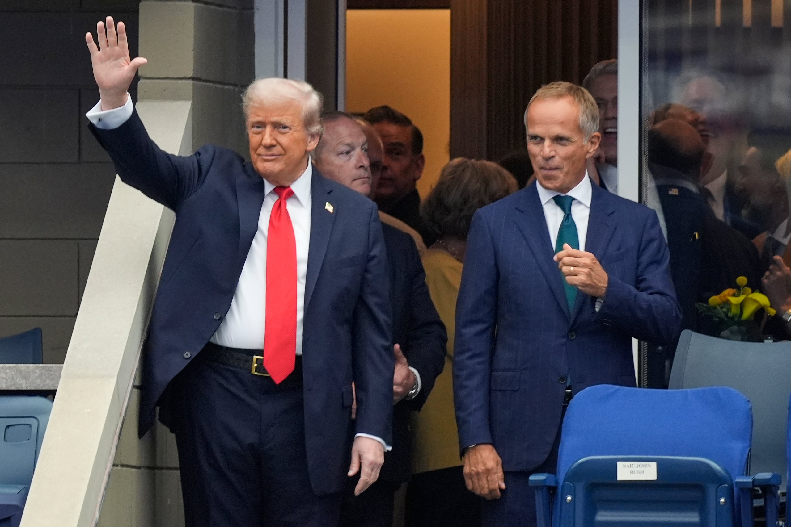 Trump saluda al público del US Open desde su espacio en el Estadio Arthur Ashe en que verá este domingo la final del evento.