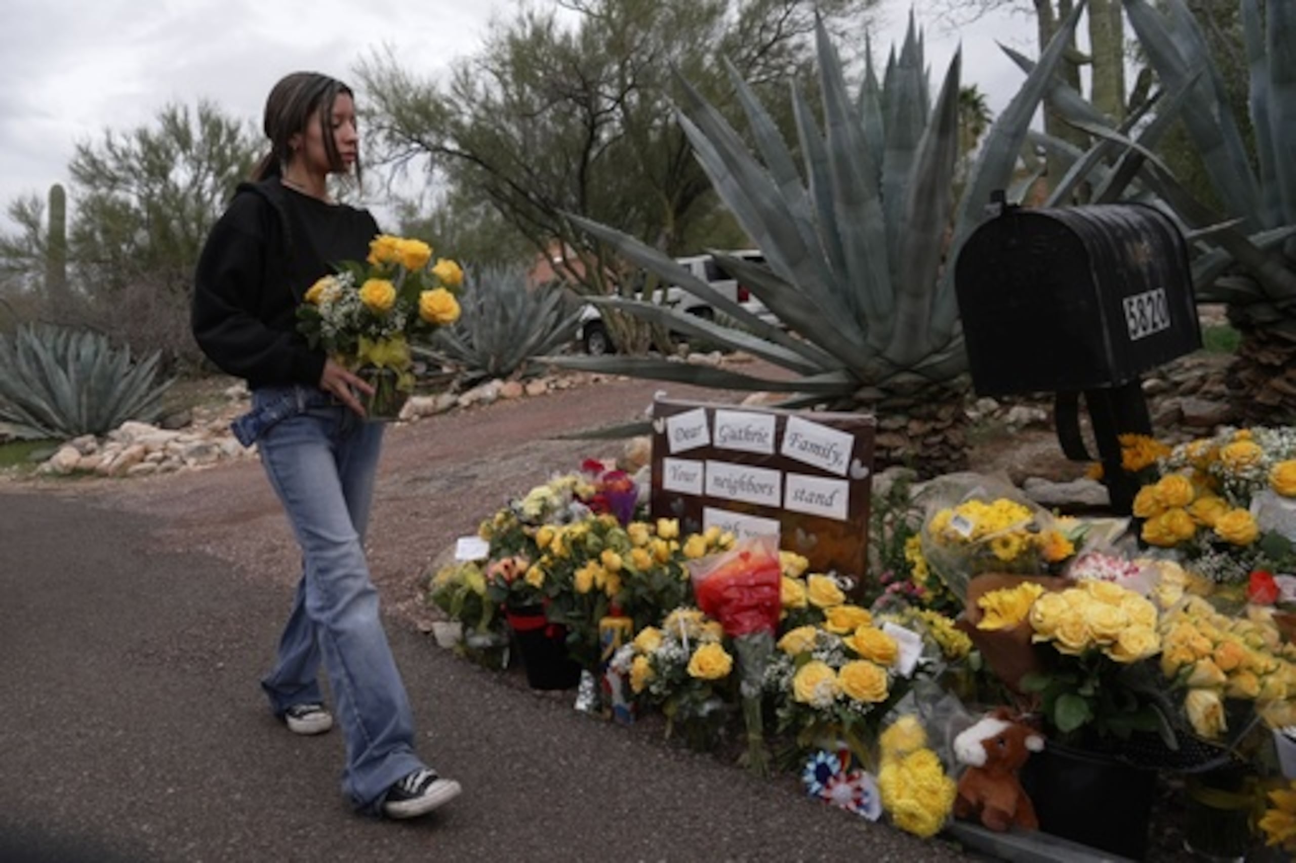 Una persona coloca flores frente a la casa de Nancy Guthrie en Tucson, Arizona, el viernes 13 de febrero de 2026. (AP Photo/Ty ONeil)