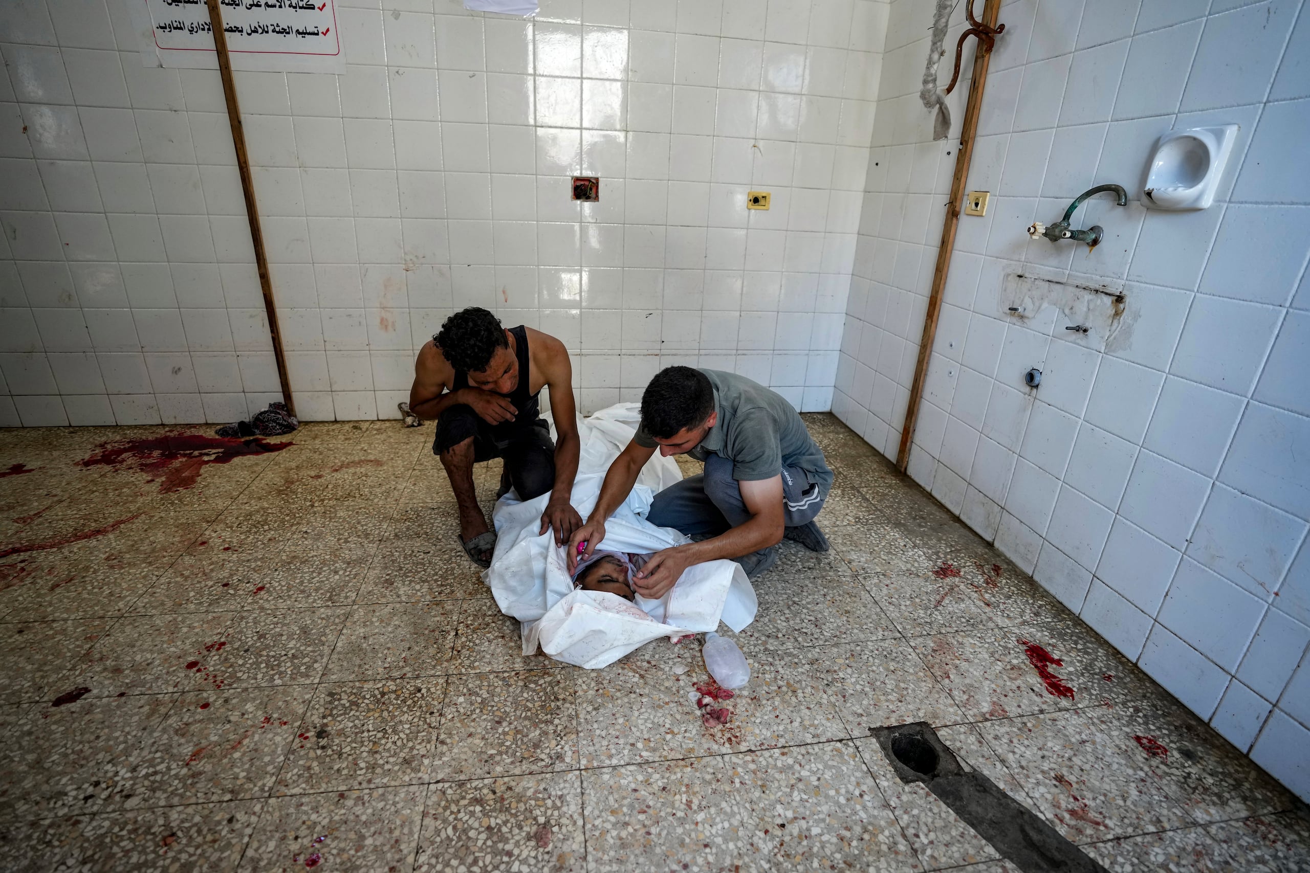 Palestinos lloran a un familiar muerto en el bombardeo israelí de la Franja de Gaza, en la morgue de un hospital de Deir al-Balah, el martes 9 de julio de 2024. (AP Foto/Abdel Kareem Hana)