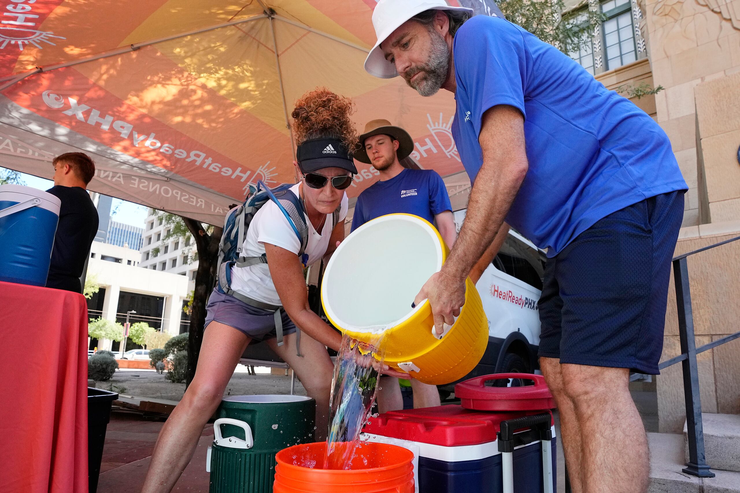 The City of Phoenix Heat Response Program team volunteers Natalie Boyd, left, and David Coughenour, right, prepare heat relief kits for the public in need as temperatures are expected to hit 119-degrees Thursday, July 20, 2023, in Phoenix. (AP Photo/Ross D. Franklin)
