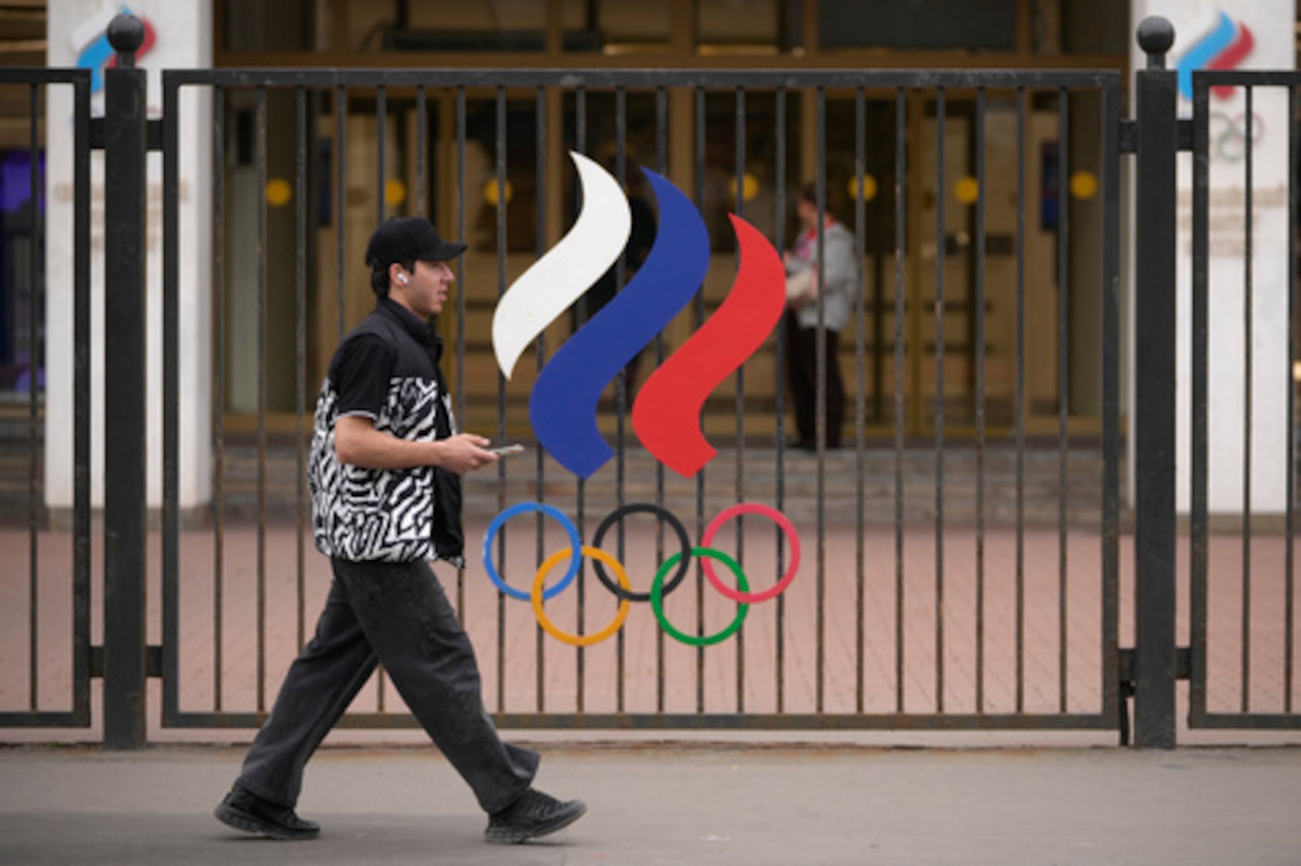 Un hombre pasa junto a una valla con los anillos olímpicos frente al edificio del Comité Olímpico Nacional de Rusia en Moscú, el martes 7 de julio de 2026. (Foto AP/Pavel Bednyakov)