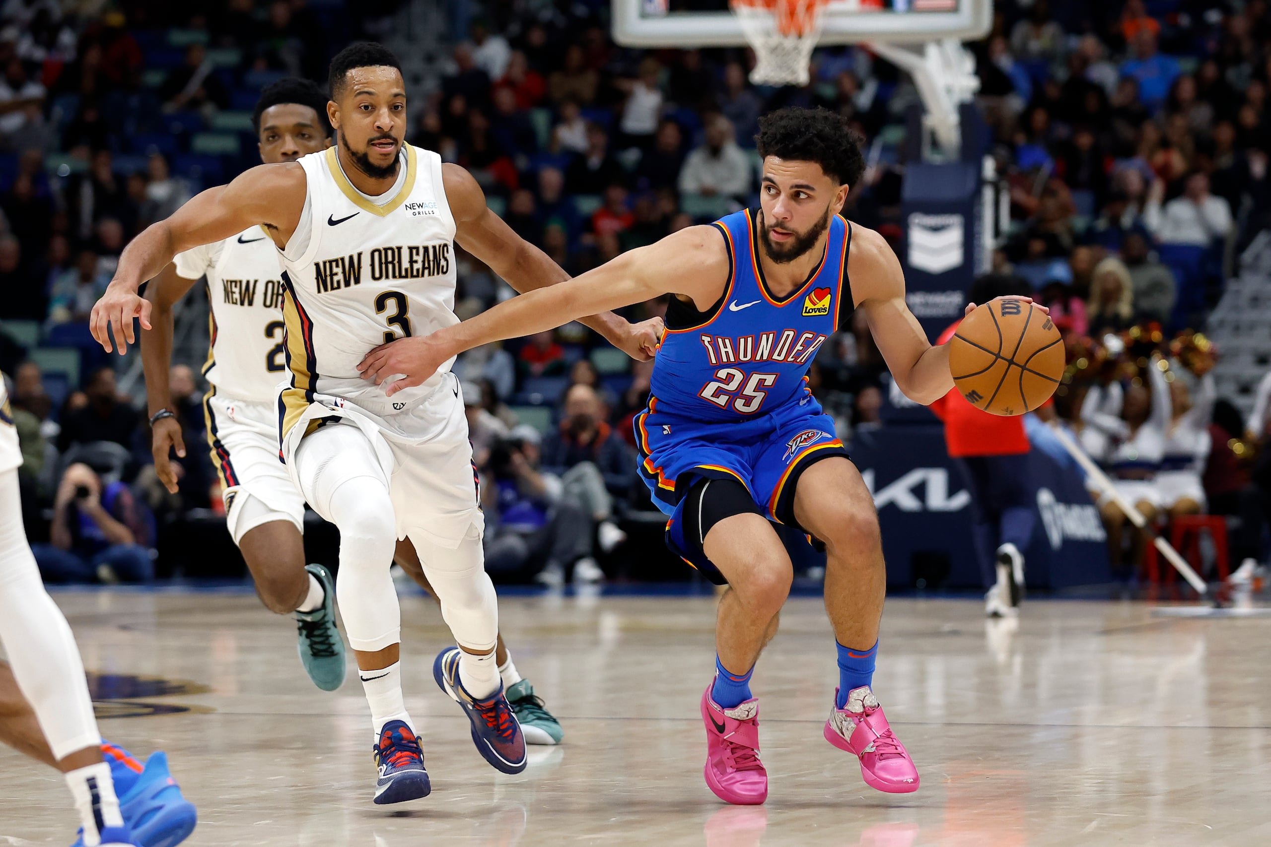 El escolta del Thunder de Oklahoma City, Ajay Mitchell (25), conduce hacia la canasta superando al escolta de los Pelicans de Nueva Orleans, CJ McCollum (3), en la segunda mitad de un partido de baloncesto de la NBA en Nueva Orleans, el sábado 7 de diciembre de 2024. El Thunder ganó 119-109. (AP Foto/Tyler Kaufman)