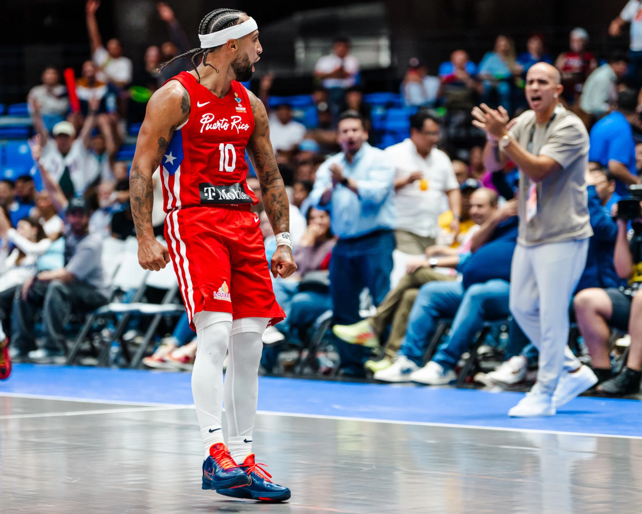 José Alvarado festeja un canasto ante Canadá en la AmeriCup 2025, mientras es aplaudido por el gerente general del Equipo Nacional, Carlos Arroyo.