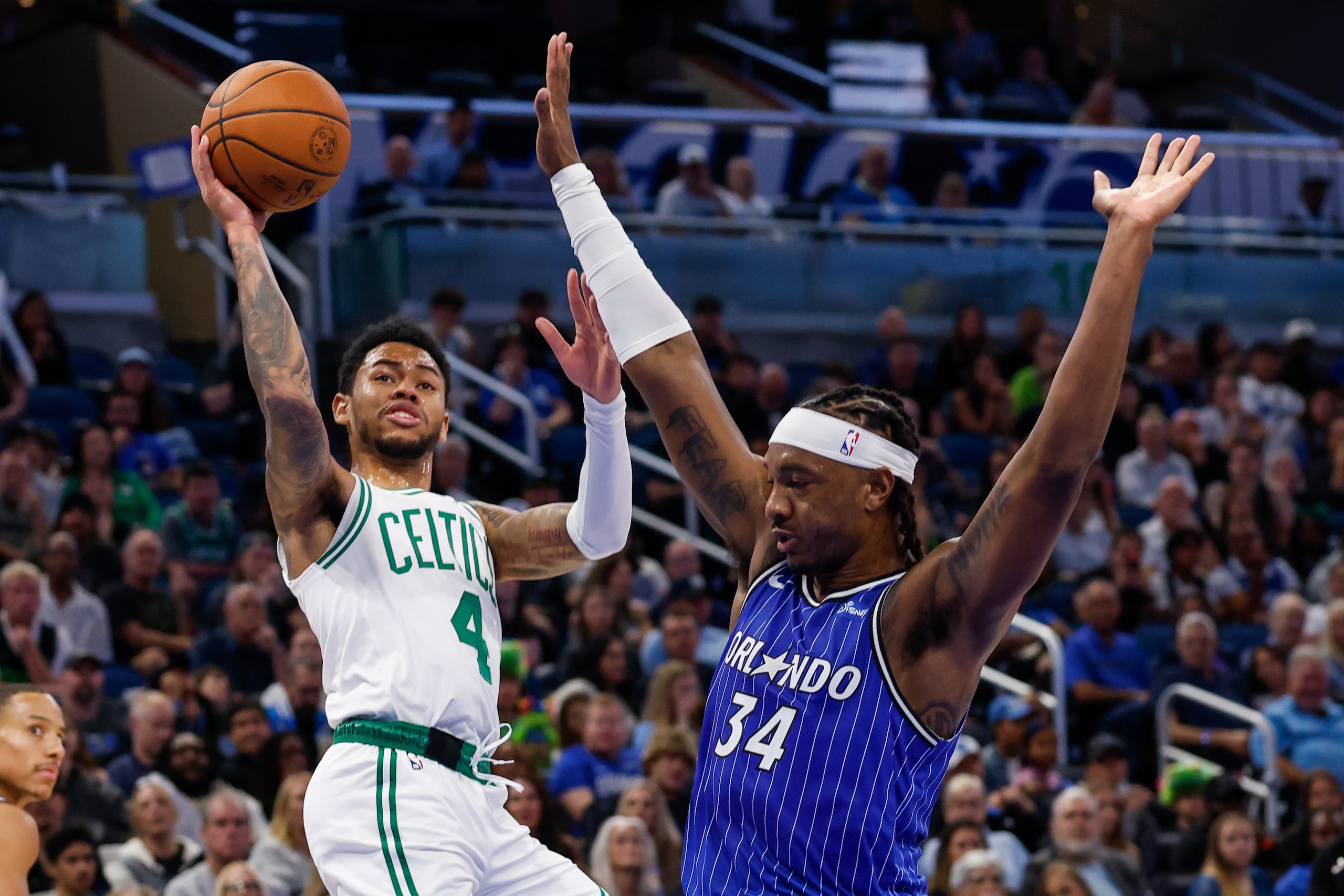 El base de los Celtics de Boston, Anfernee Simons (4), lanza dos puntos mientras recibe una falta del pívot del Magic de Orlando, Wendell Carter Jr. (34), durante la primera mitad de un juego de baloncesto de la NBA, el domingo 9 de noviembre de 2025, en Orlando, Florida. (Foto AP/Kevin Kolczynski)