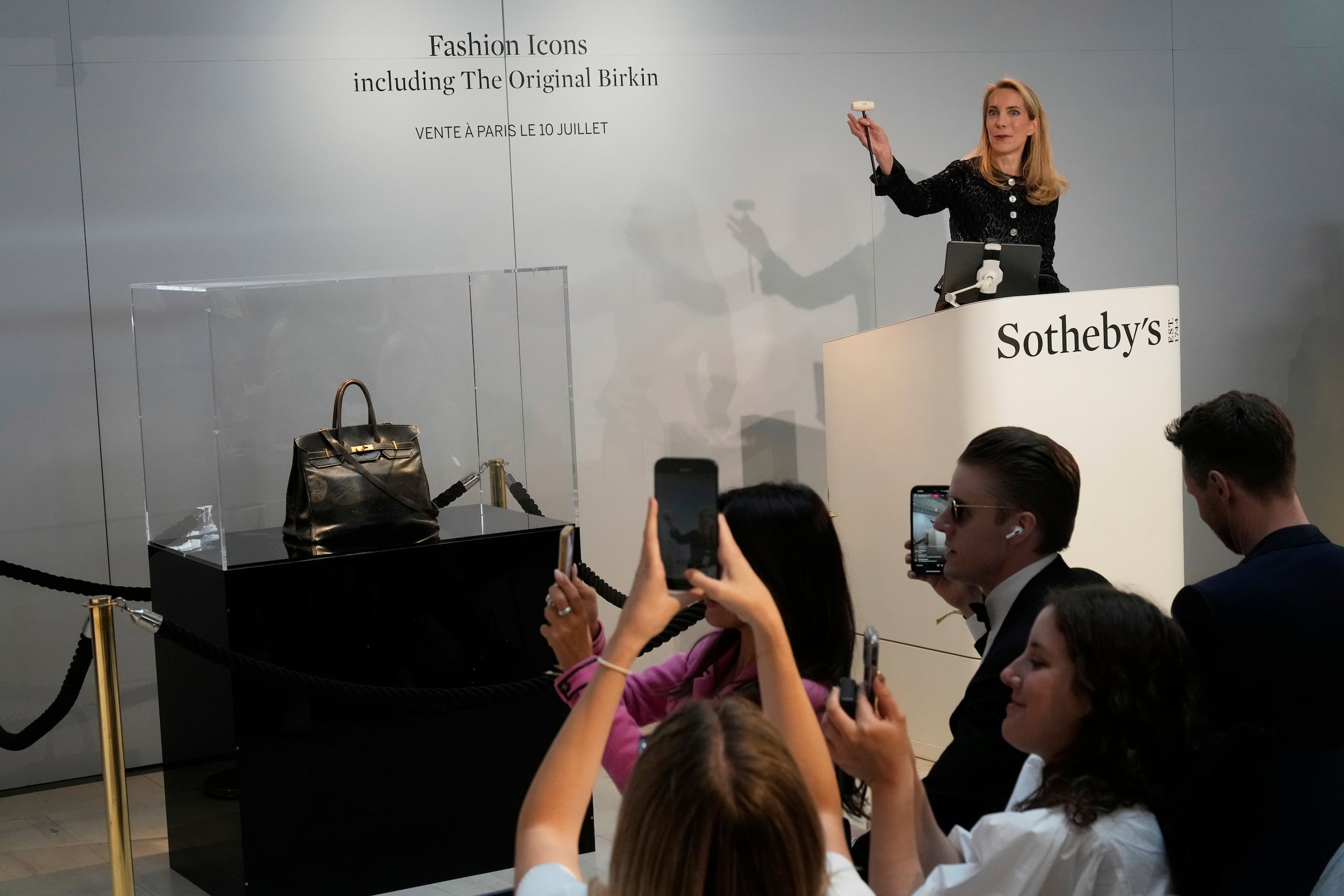La funcionaria de subastas Aurélie Vandevoorde hace un gesto mientras el bolso Birkin original creado por Hermès para Jane Birkin se vendió en una subasta por 7 millones de euros o 8,2 millones de dólares, el jueves 10 de julio de 2025 en París. (AP Photo/Michel Euler)