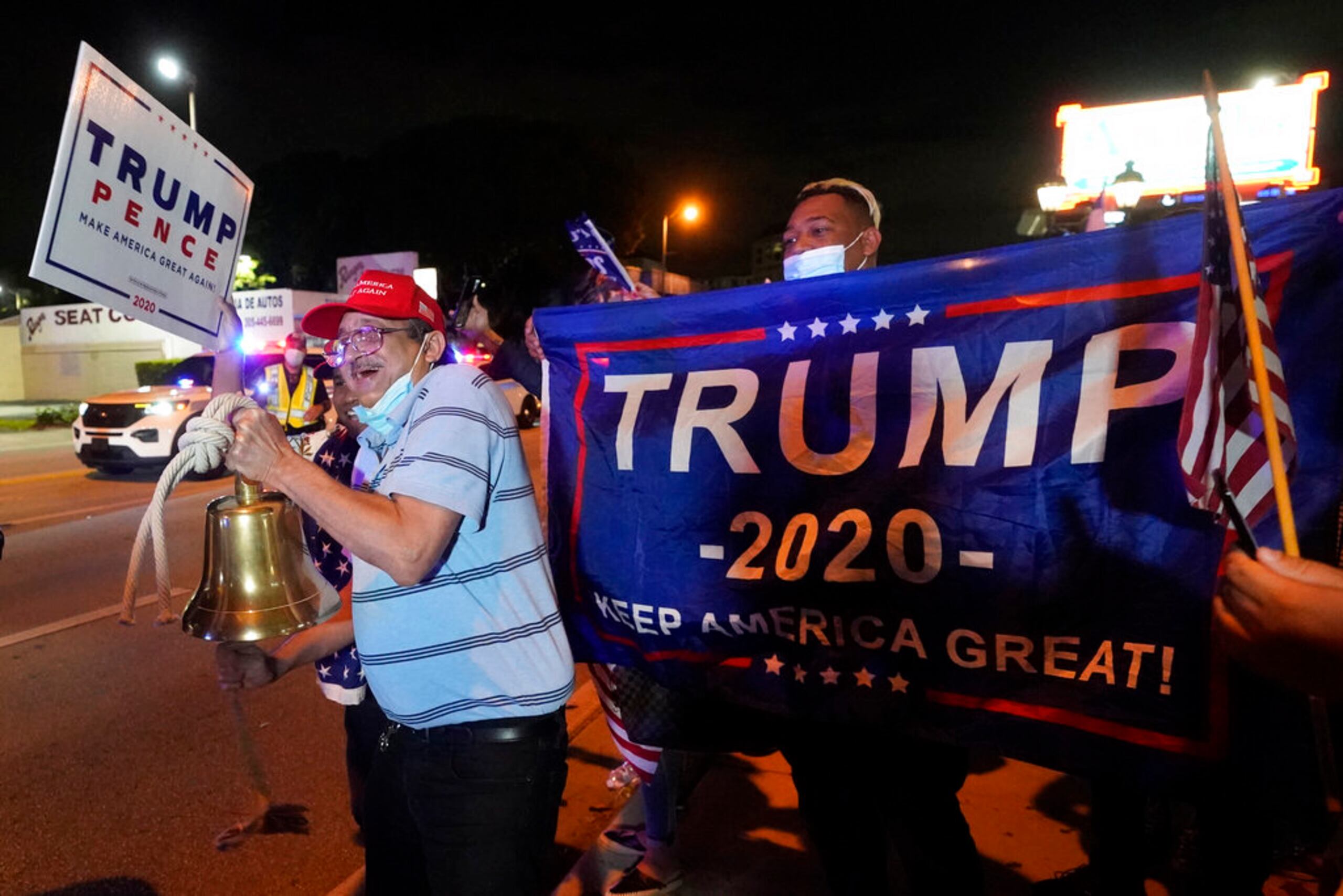 Rafael Fagundo toca una campana mientras él y otros simpatizantes del presidente Donald Trump corean consignas y ondean banderas frente al restaurante cubano Versailles la noche de las elecciones, en el vecindario Pequeña Habana de Miami.