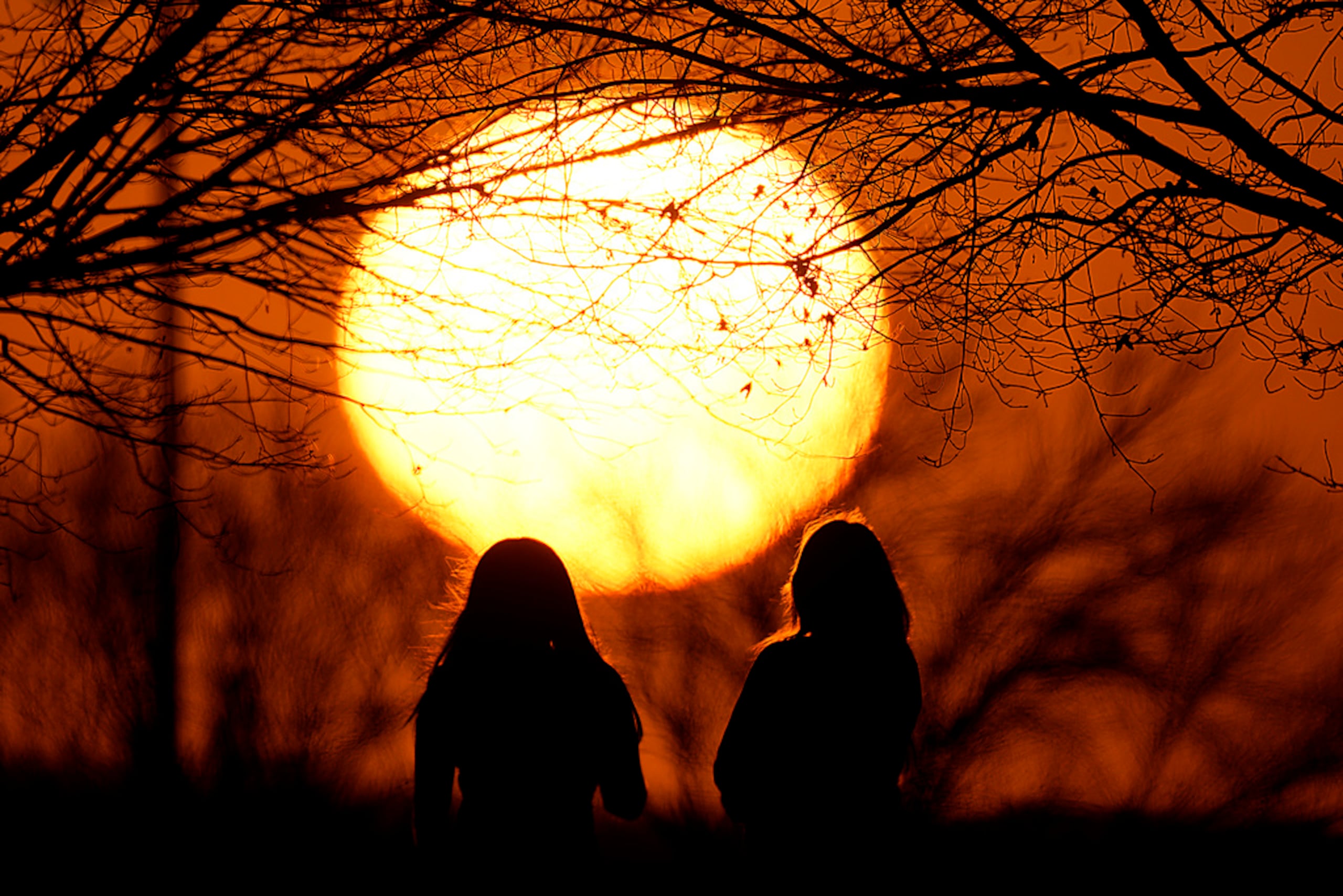 Personas miran la puesta de sol en un parque, en un día inusualmente cálido, el domingo 25 de febrero de 2024 en Kansas City, Missouri.