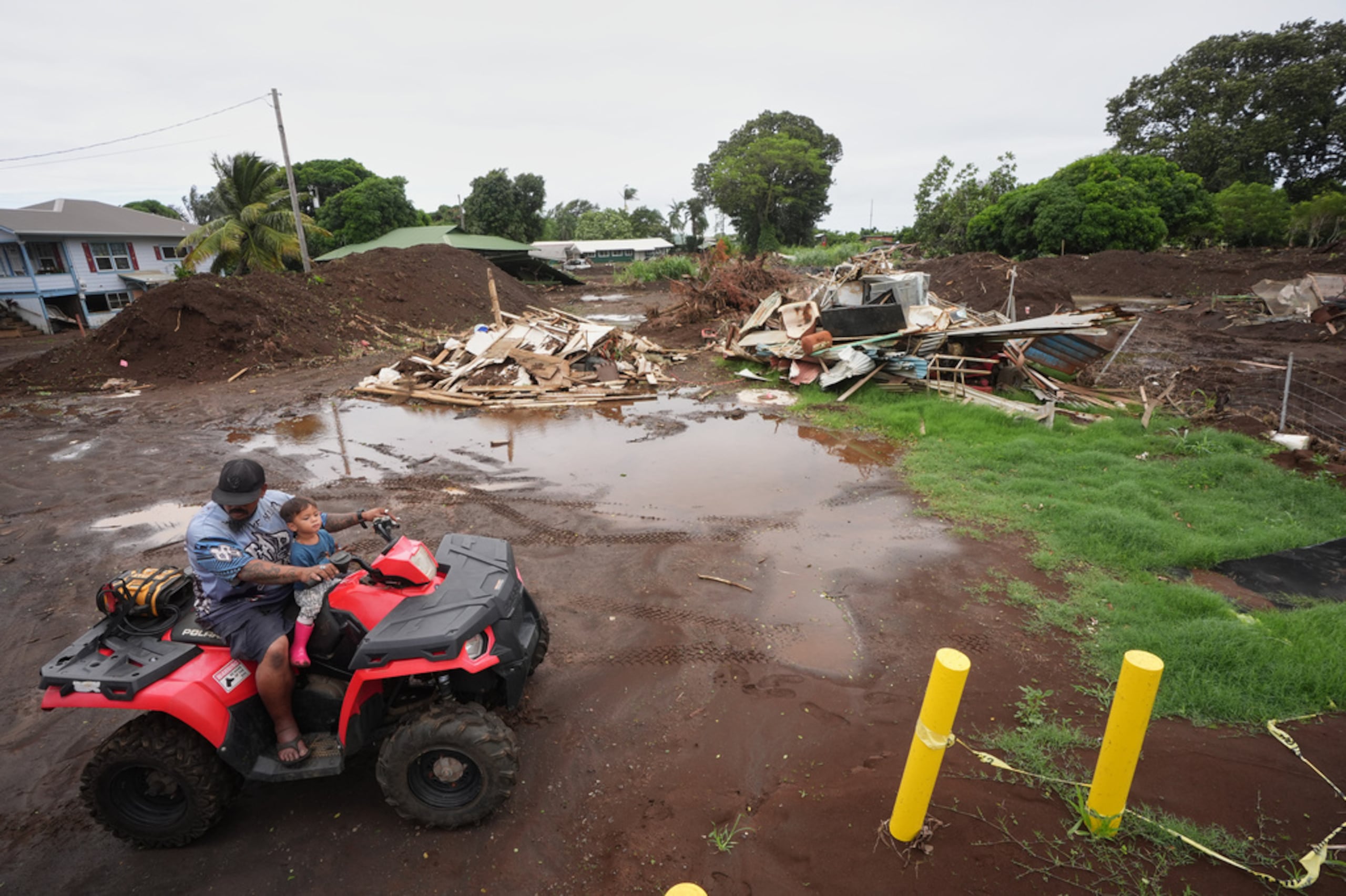 Un hombre se desplaza con su hijo cerca de una casa destruida el mes anterior al paso del huracán Lala, mientras las inundaciones del huracán Nolo retroceden, el domingo 27 de septiembre de 2026, en Naalehu, Hawai.