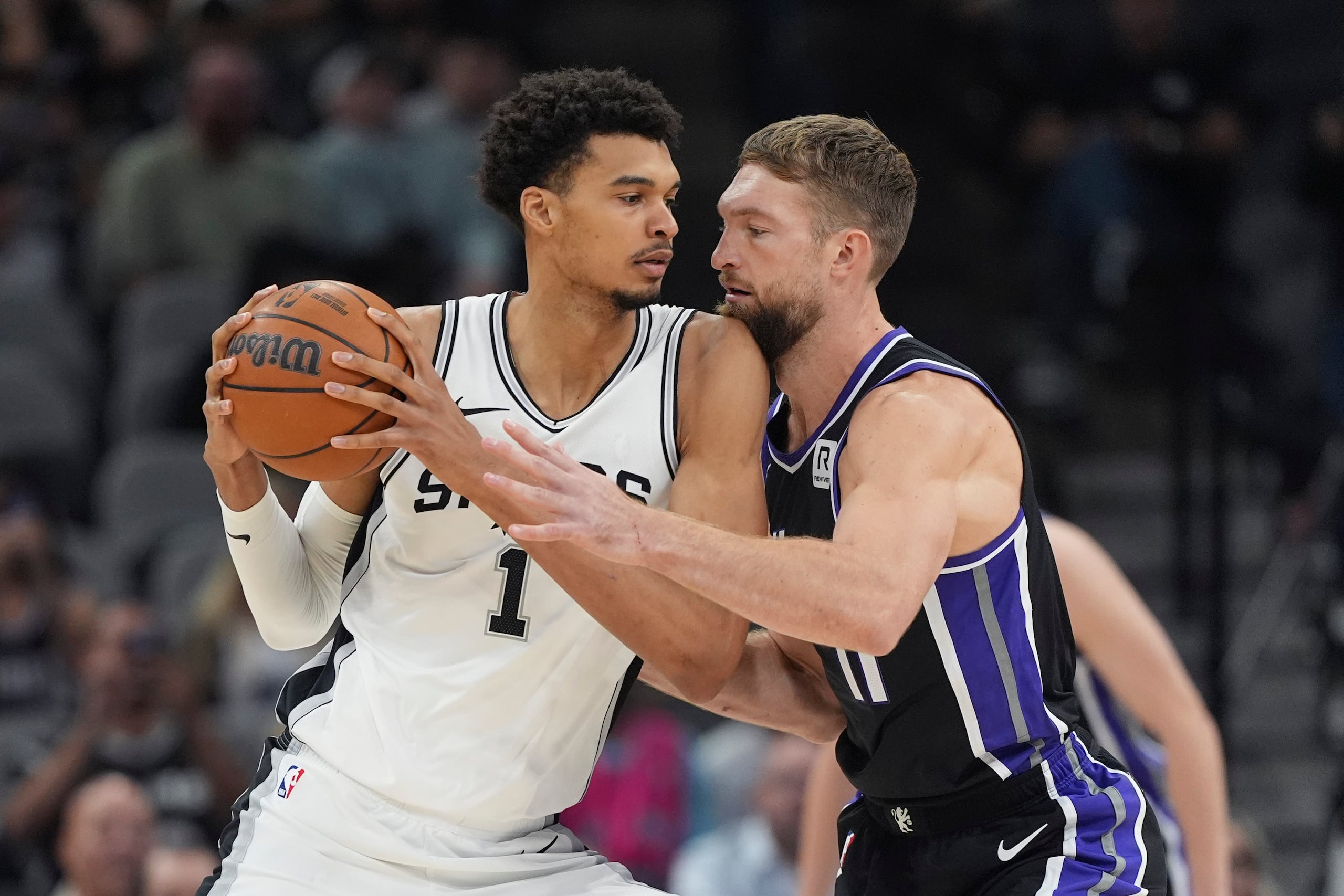 El pívot de los Spurs de San Antonio Victor Wembanyama siendo defendido por el alero de los Kings de Sacramento Domantas Sabonis en el enucentro del lunes 11 de noviembre del 2024. (AP Foto/Eric Gay)