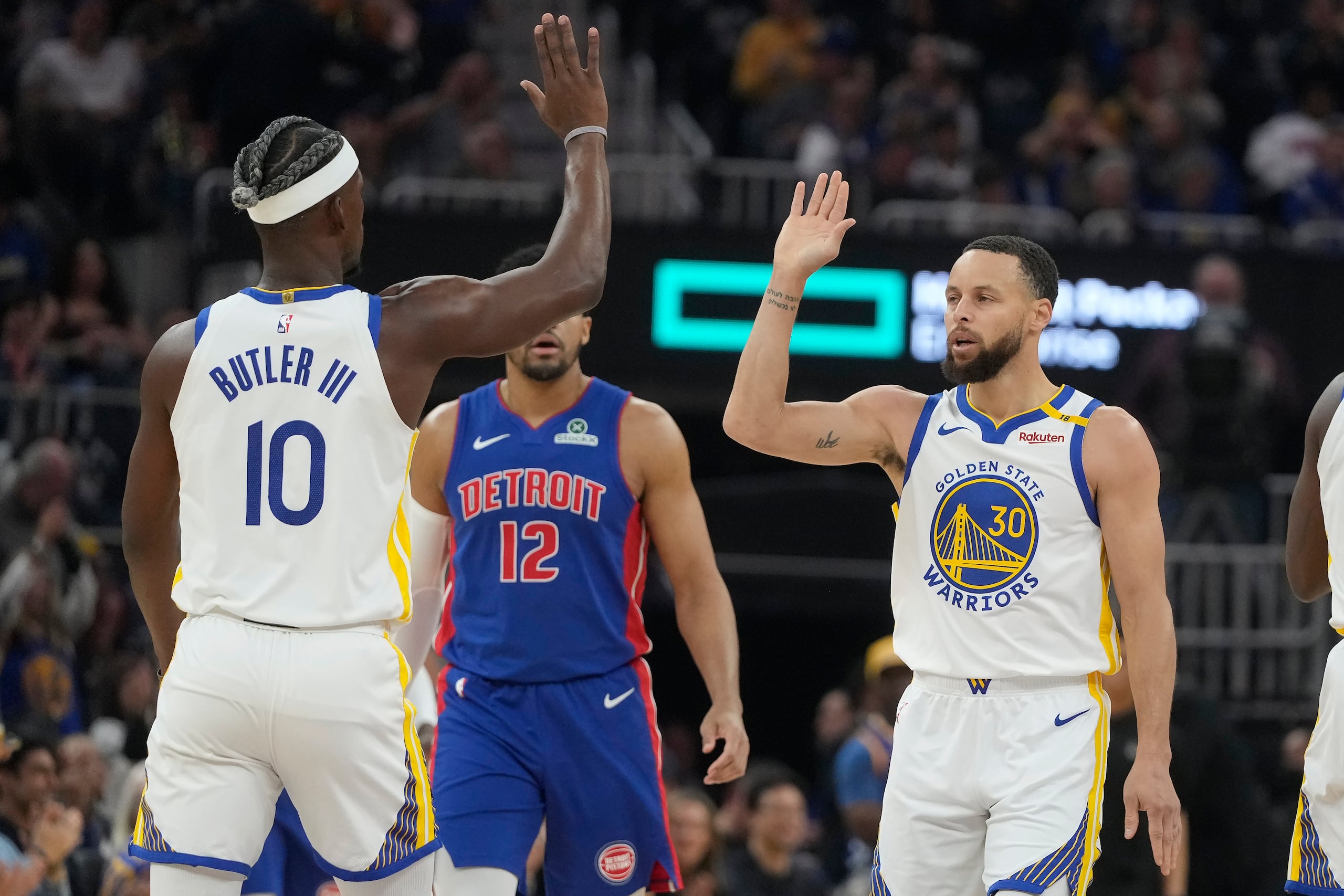 El escolta de los Warriors de Golden State, Stephen Curry (30), es felicitado por el alero Jimmy Butler III (10) después de hacer una canasta de tres puntos durante la primera mitad de un partido de baloncesto de la NBA contra los Pistons de Detroit en San Francisco.