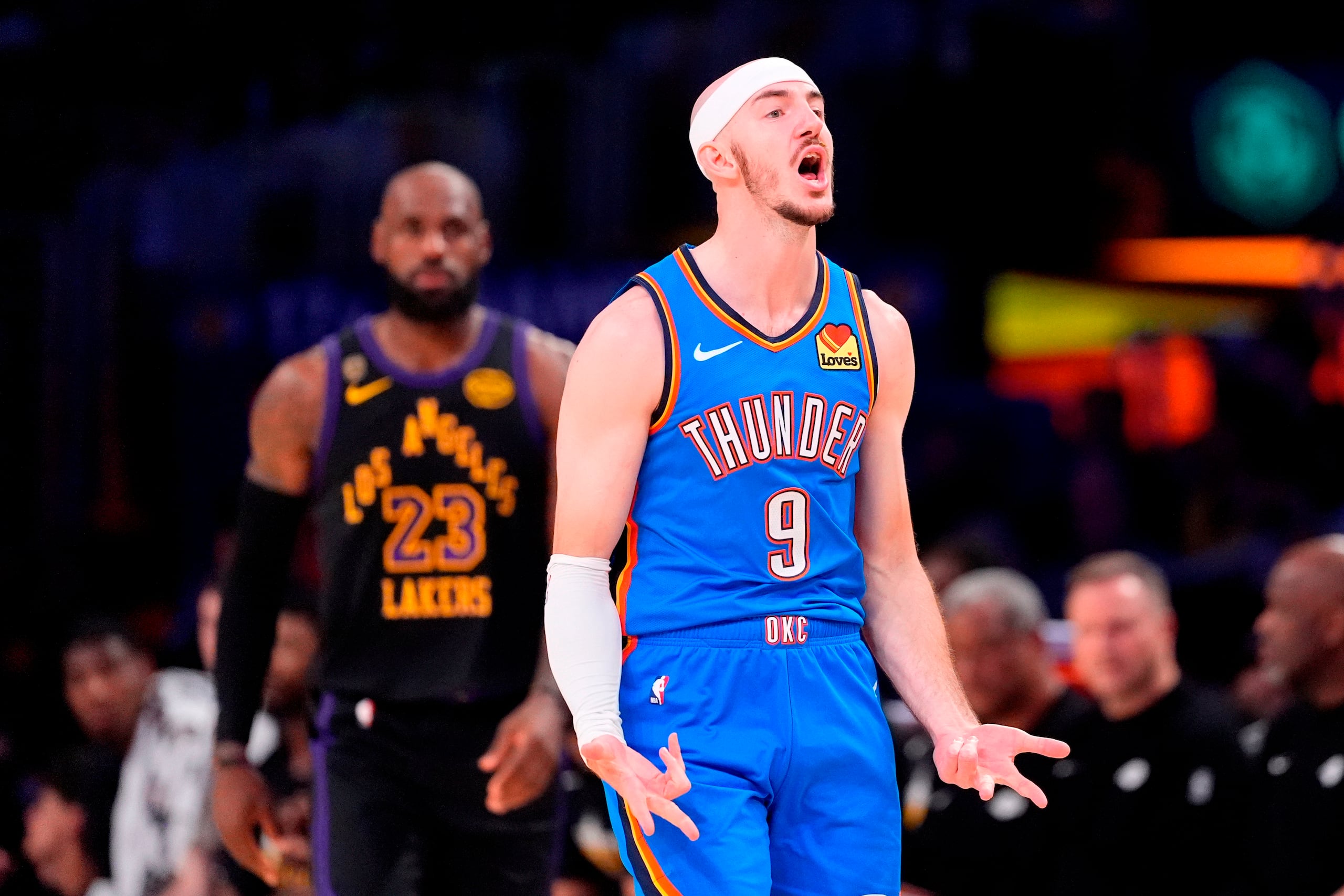 Alex Caruso (9) del Thunder de Oklahoma City, celebra después de encestar mientras en el fondo observa LeBron James, durante la primera mitad del cuarto juego de la serie segunda ronda de los playoffs del baloncesto de la NBA, el lunes 11 de mayo de 2026, en Los Ángeles. (AP Foto/Mark J. Terrill)