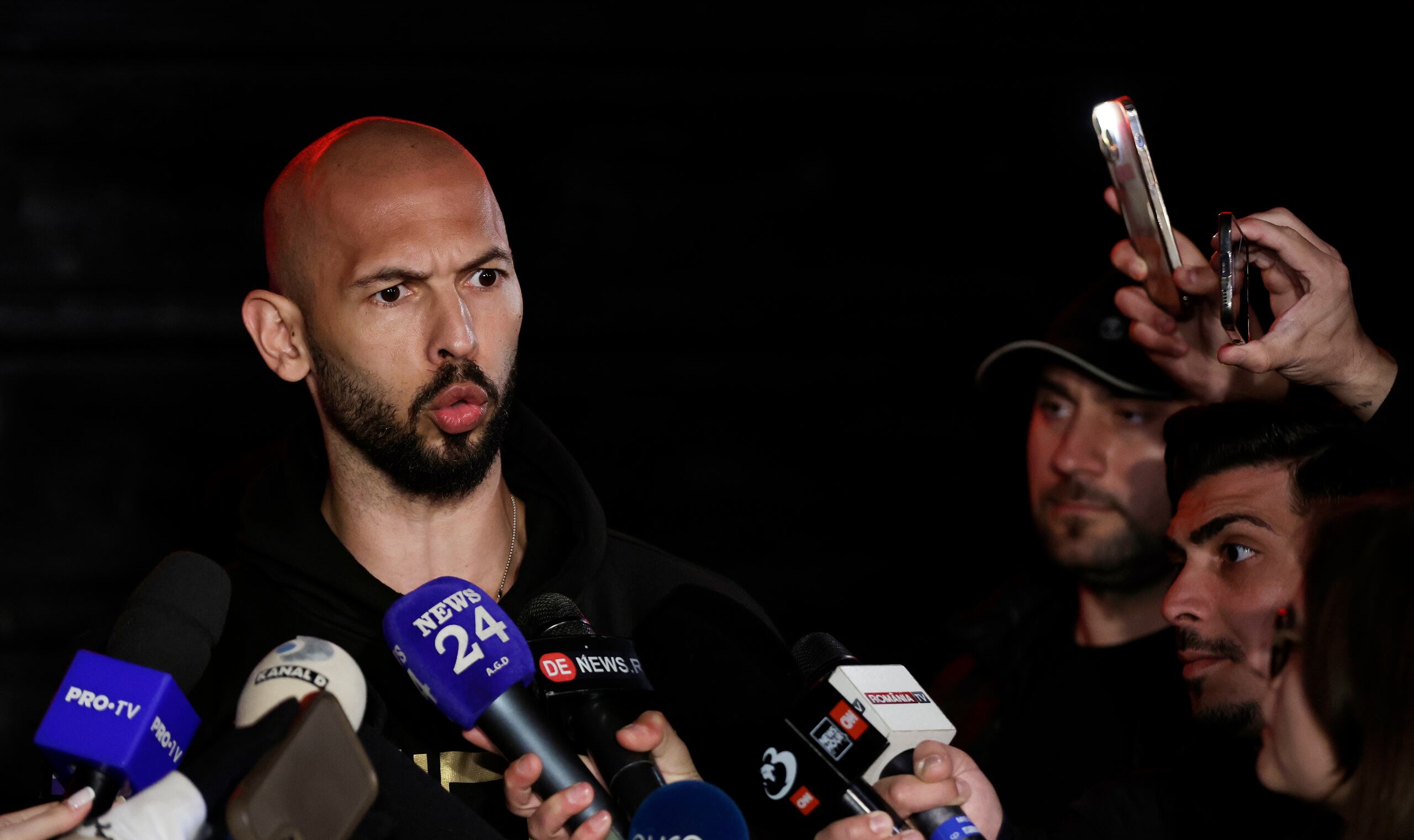 El exkickboxer profesional y influencer de redes sociales Andrew Tate habla con reporteros de televisión después de regresar de Estados Unidos, frente a su propiedad, en Bucarest, el 22 de marzo de 2025. (EFE/EPA/Robert Ghement)