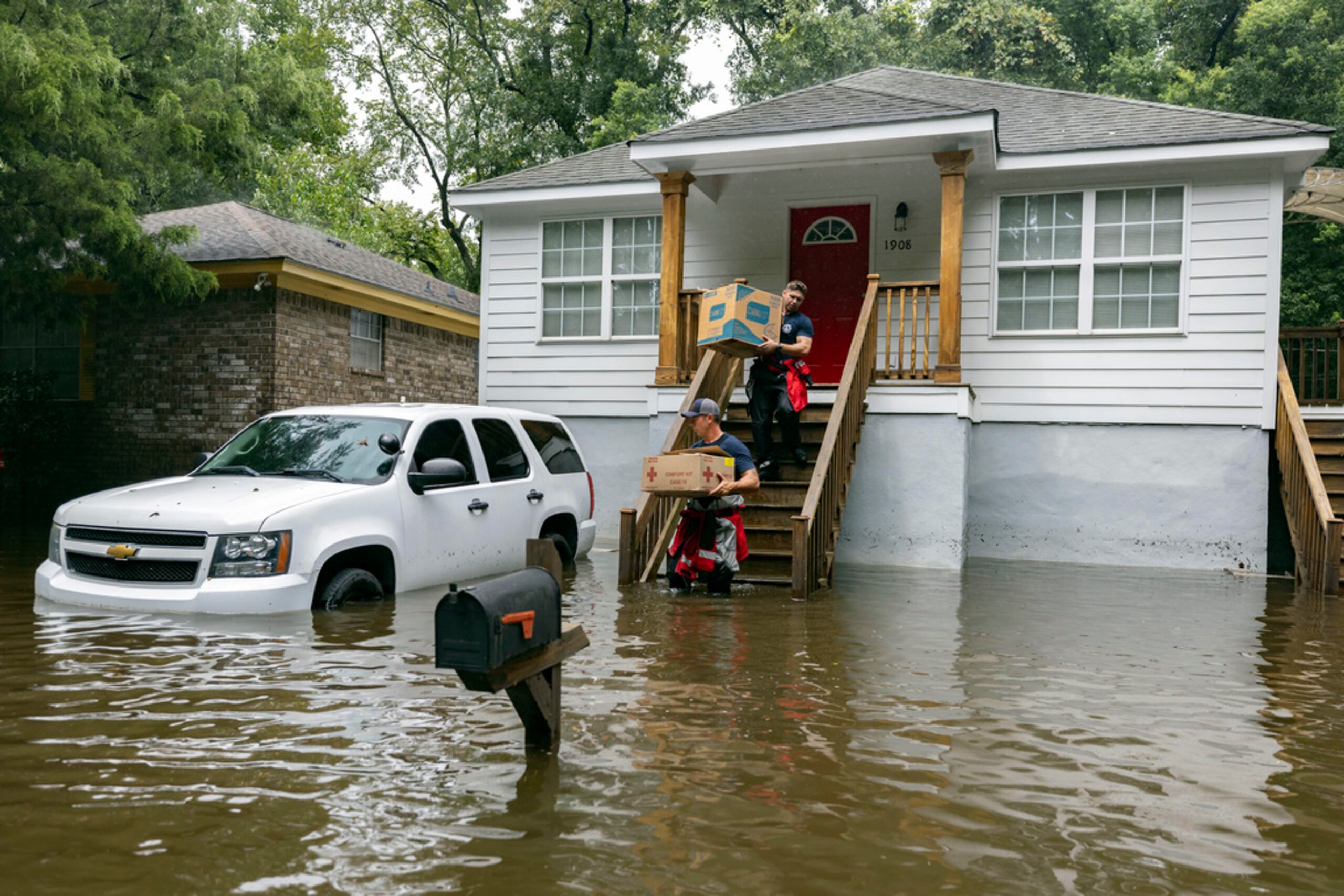 Los bomberos Ron Strauss y Andrew Stevenson llevan comida a los habitantes del barrio Tremont Park que quedaron atrapados por las inundaciones causadas por la tormenta tropical Debby, el 6 de agosto de 2024 en Savannah, Georgia.