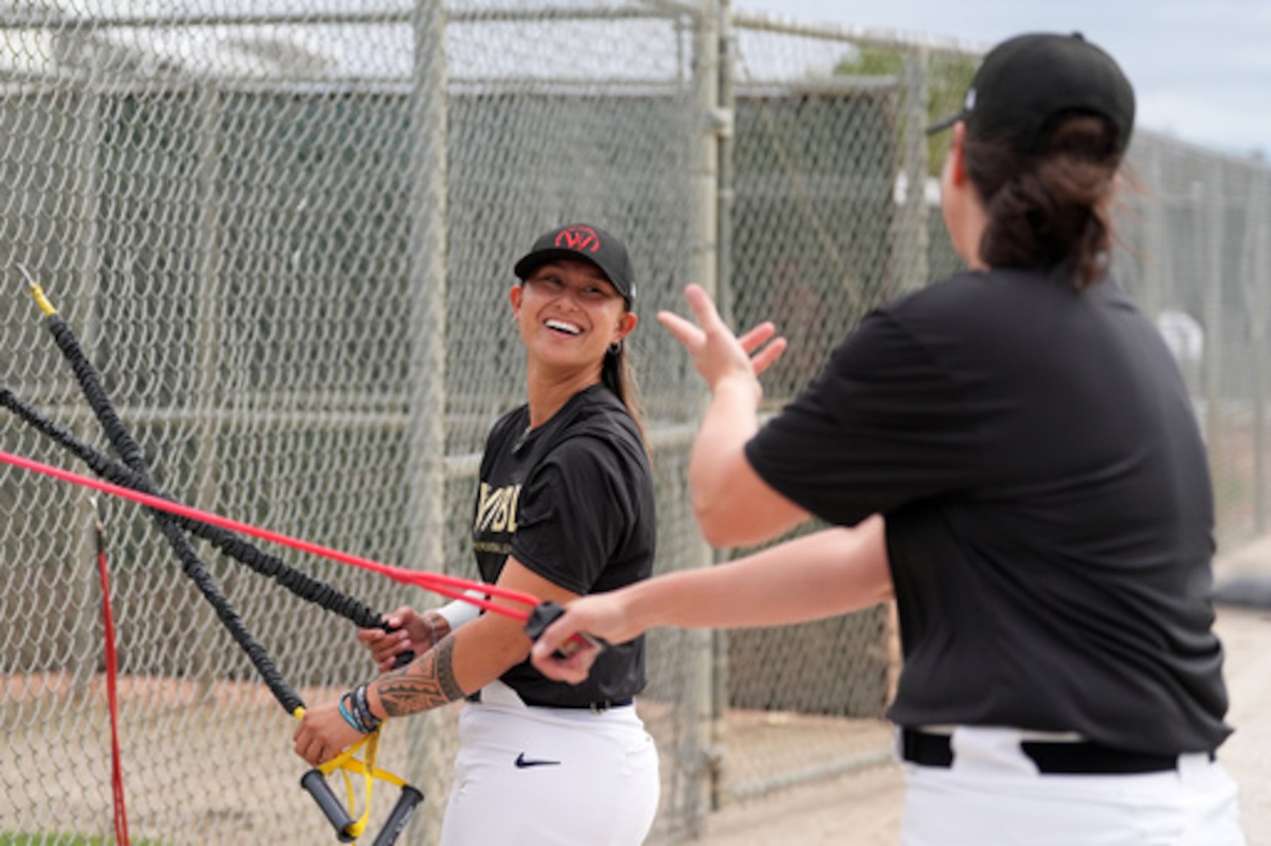 Kelsie Whitmore habla con otra jugadora mientras usan bandas de resistencia durante una práctica de la Liga Femenina Profesional de Béisbol (WPBL), el miércoles 18 de marzo de 2026, en Fort Myers, Florida (AP Photo/Rebecca Blackwell).