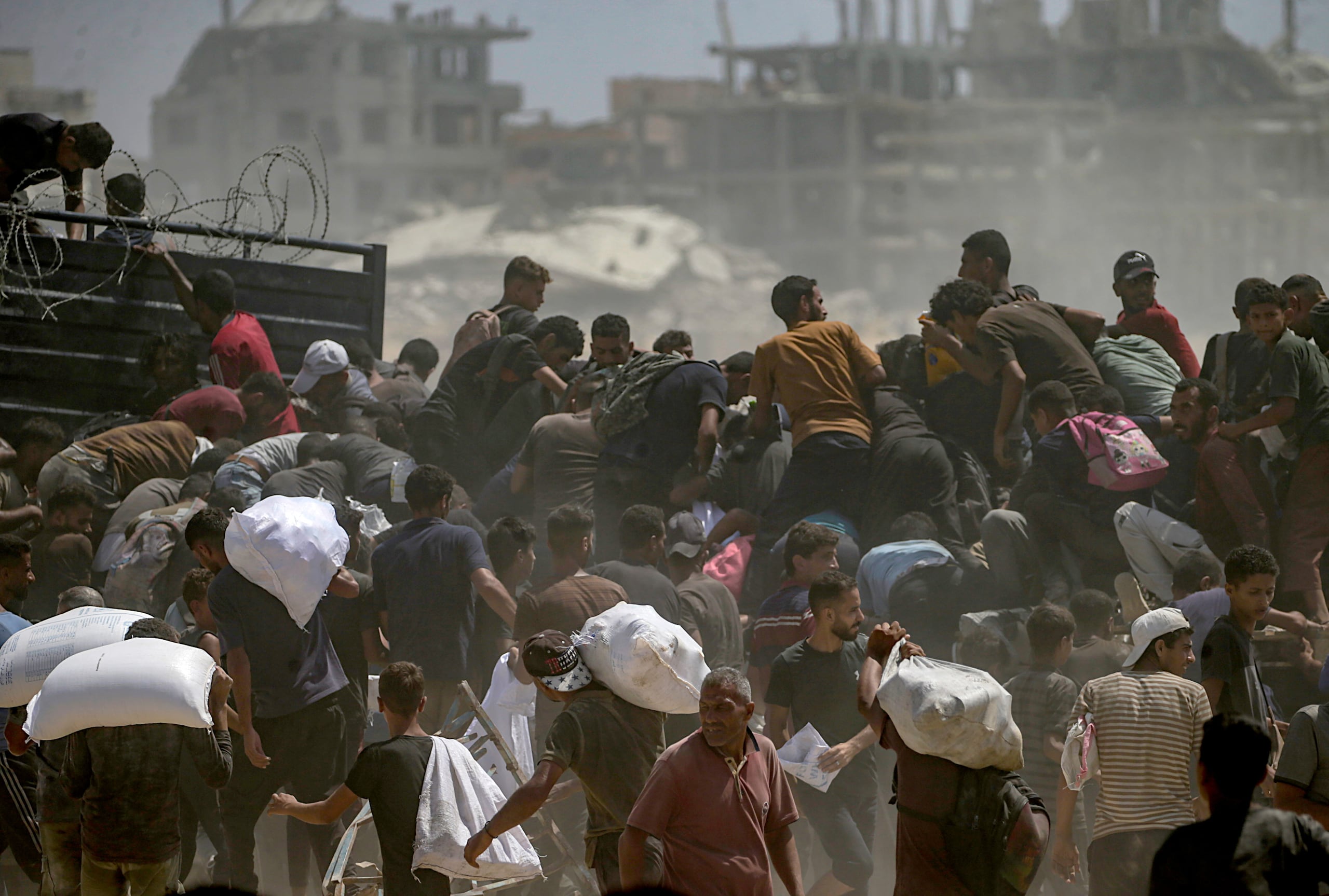 Palestinos desplazados internamente intentan conseguir bolsas de harina de un camión de ayuda cerca de un punto de distribución de alimentos en Zikim, en el norte de la Franja de Gaza, el 8 de agosto de 2025. (EFE/EPA/MOHAMMED SABER)