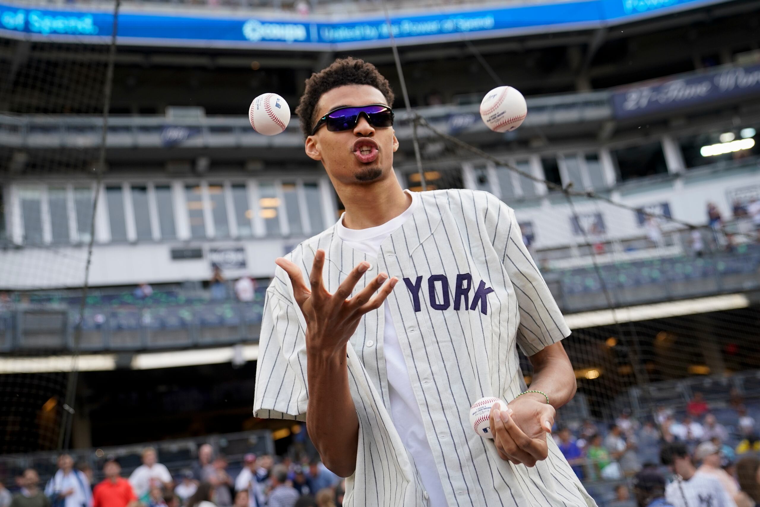 El basquetbolista francés Victor Wembanyama, señalado para ser la primera selección del draft de la NBA, se dispone a hacer el primer lanzamiento del juego del martes 20 de junio de 2023, entre los Yankees de Nueva York y los Mariners de Seattle.