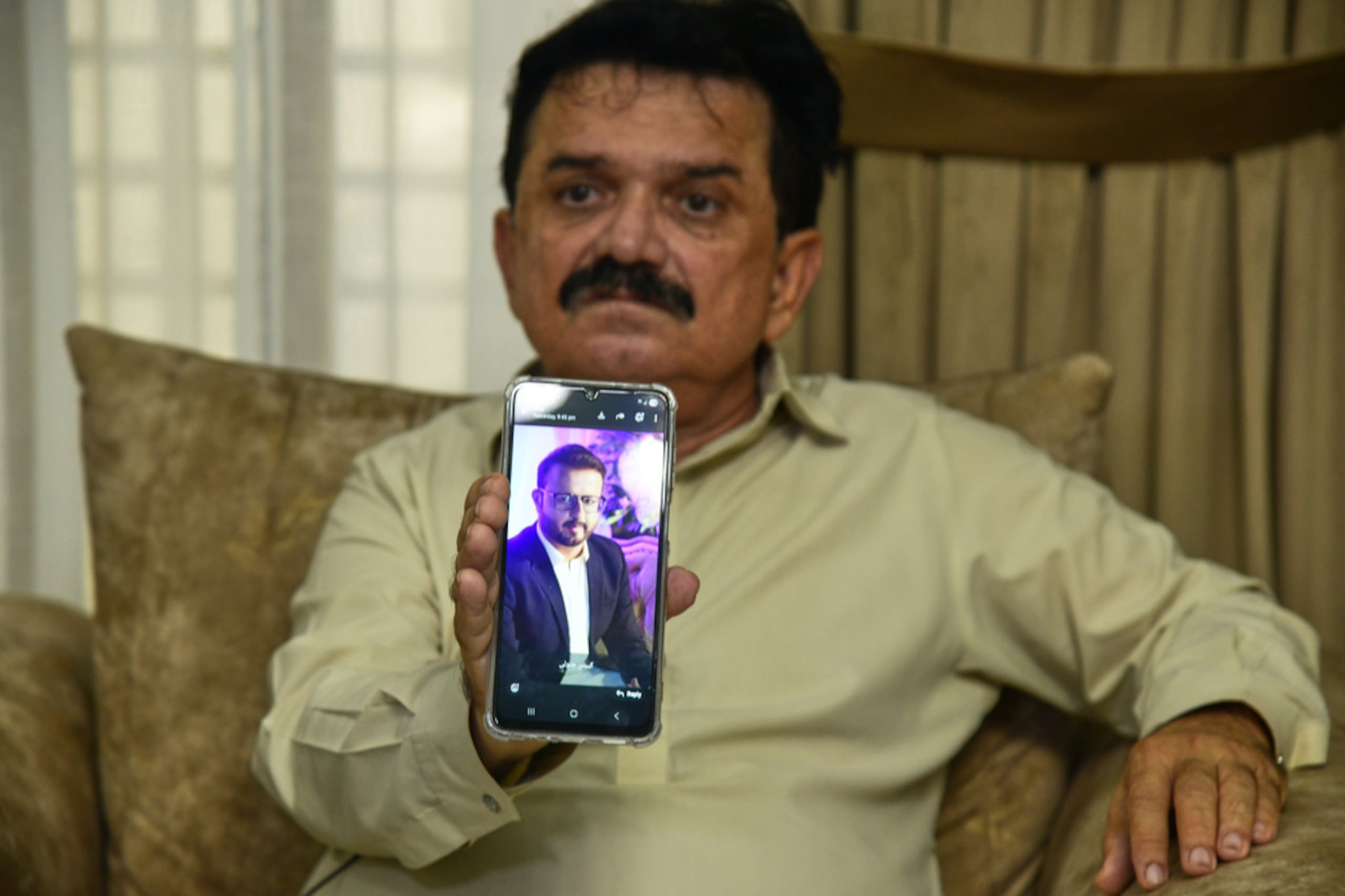 Ghulam Nabi Bahrani, suegro del copiloto Faisal Jatoi, miembro de la tripulación del avión de carga, muestra una foto de él en un celular en Karachi, Pakistán, el 8 de julio de 2026.