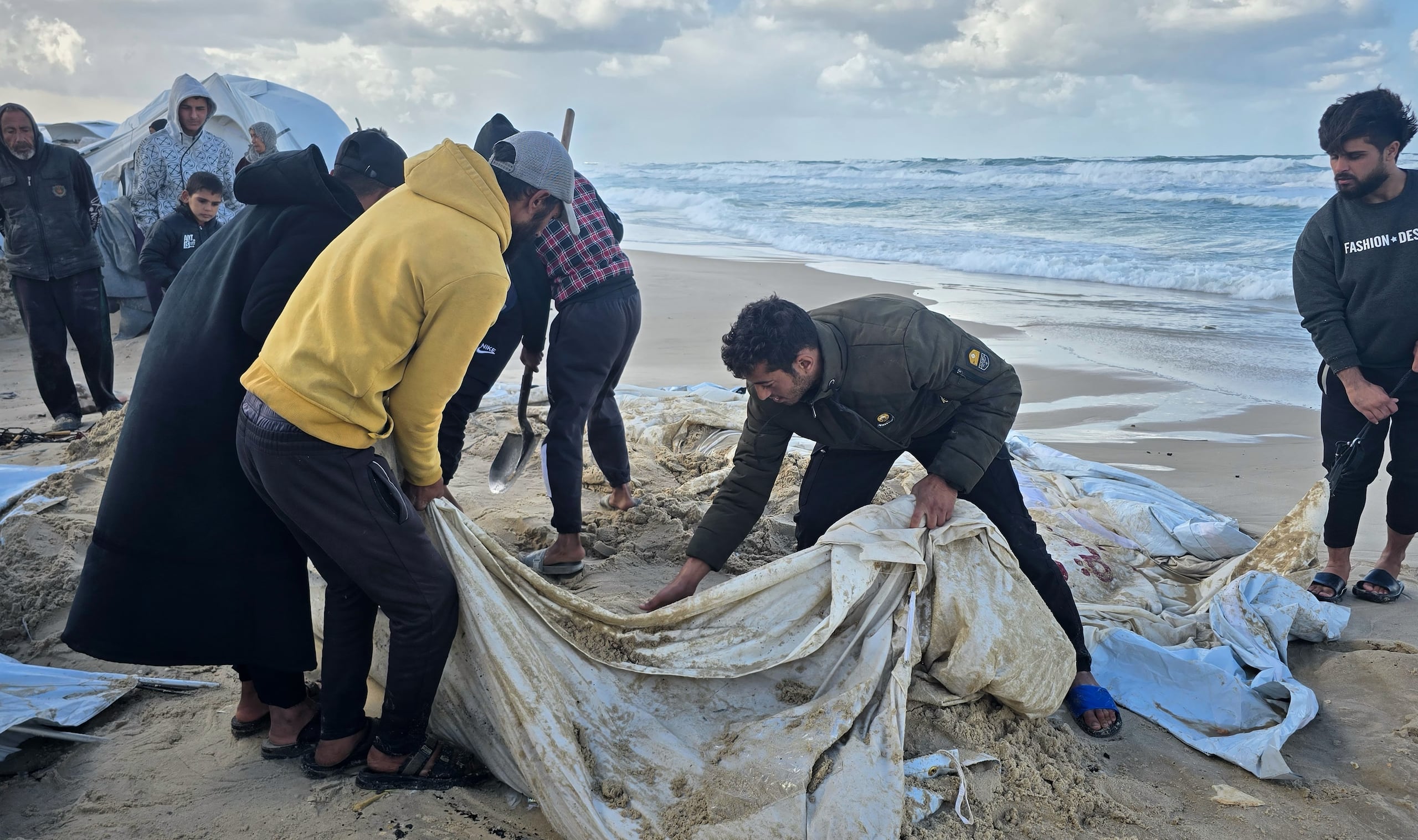 Palestinos intentan recuperar su tienda de campaña después de que lluvias nocturnas inundaran su campamento junto a la playa en Jan Yunis, el domingo 28 de diciembre de 2025, en el sur de la Franja de Gaza. (AP Foto/Mohammad Jahjouh)