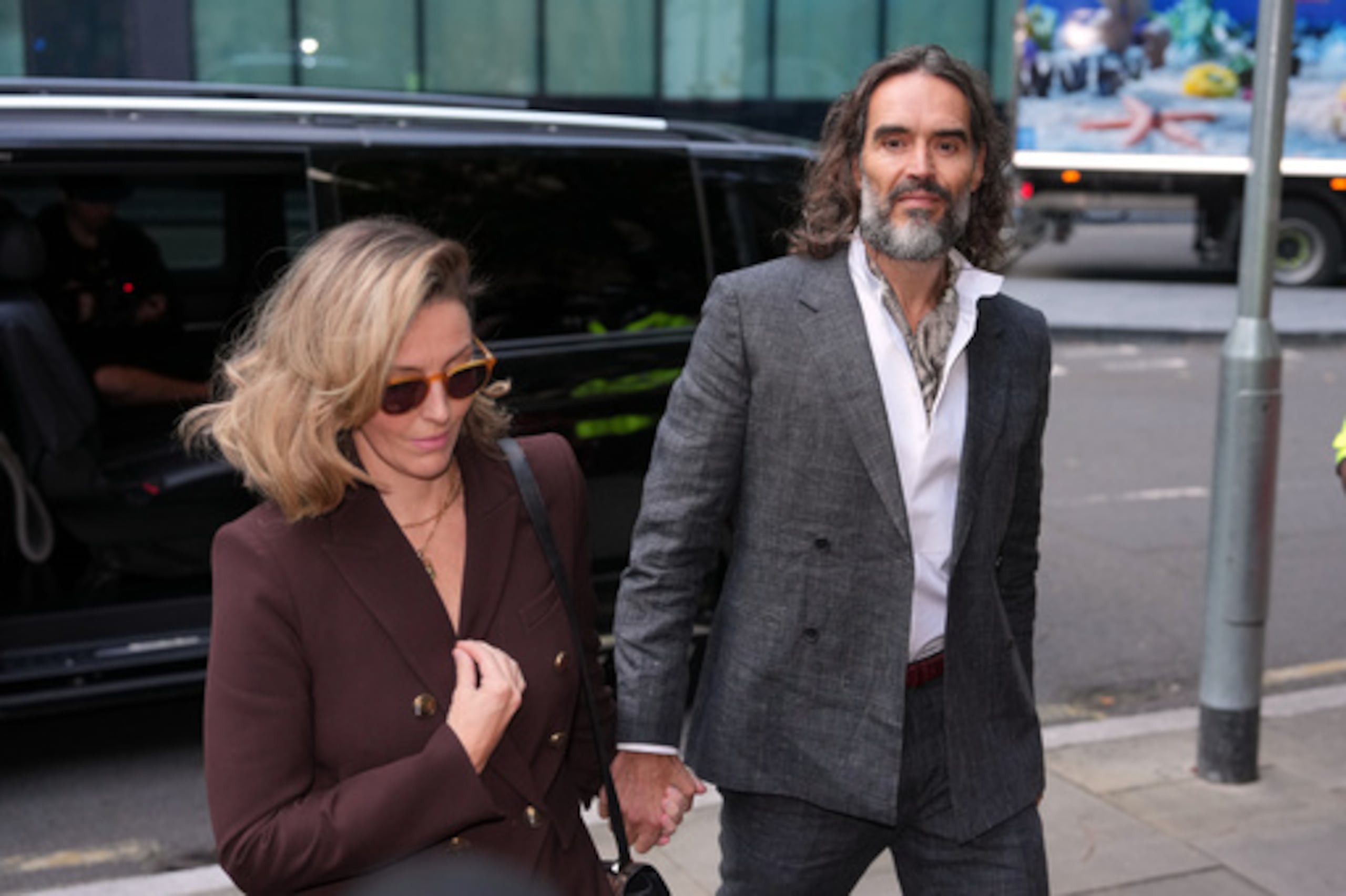 El cómico y actor Russell Brand, acompañado de su esposa Laura Brand, llega al Tribunal Penal de Southwark, donde se le imputan varios cargos de violación y agresión sexual contra seis mujeres, que él ha negado, en Londres, el lunes 12 de octubre de 2026. (Foto AP/Kin Cheung)