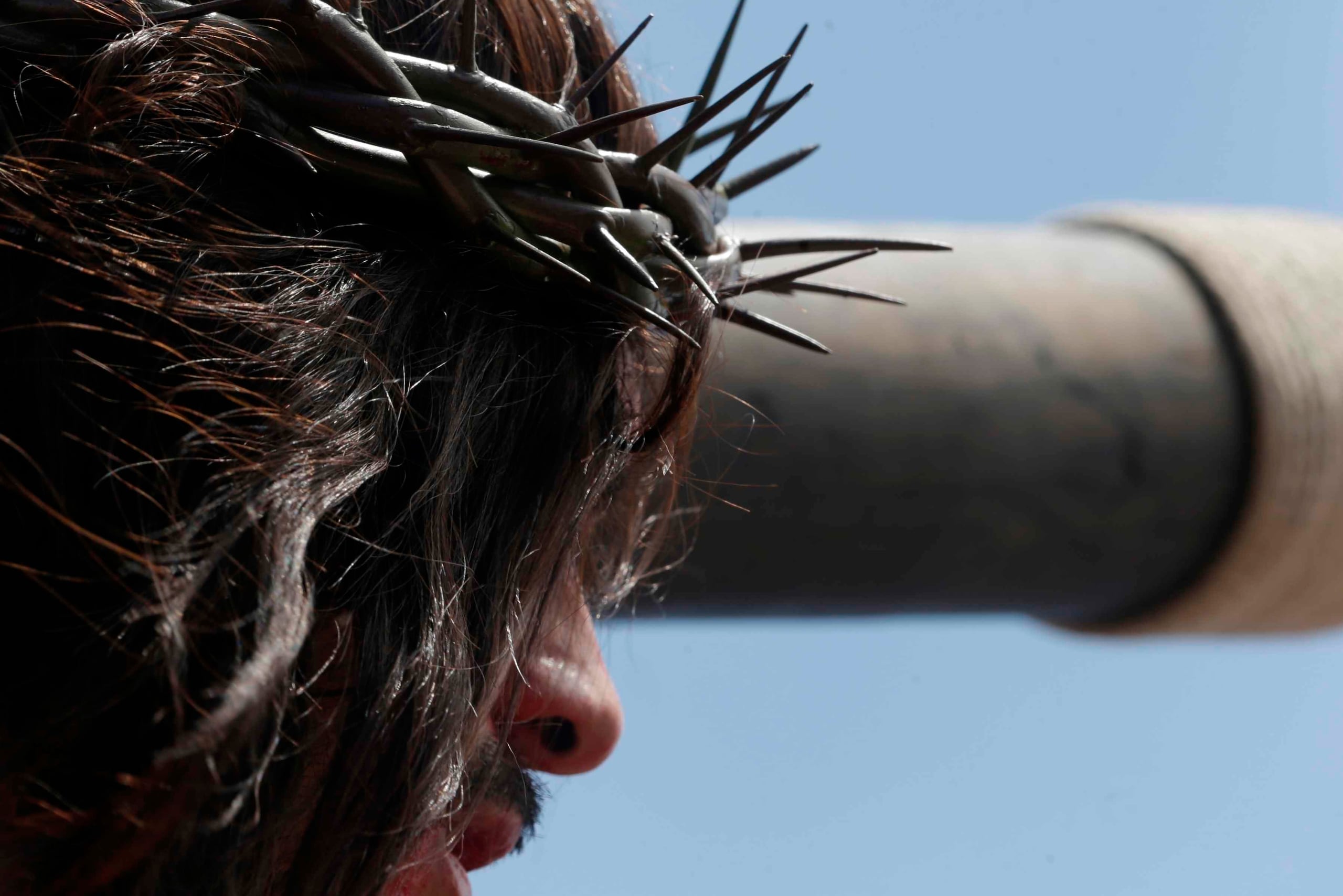 Un creyente interpreta a Jesucristo que mira hacia las cuerdas en una cruz durante una representación del vía crucis con motivo del Viernes Santo en San Joaquín de Flores, Costa Rica.