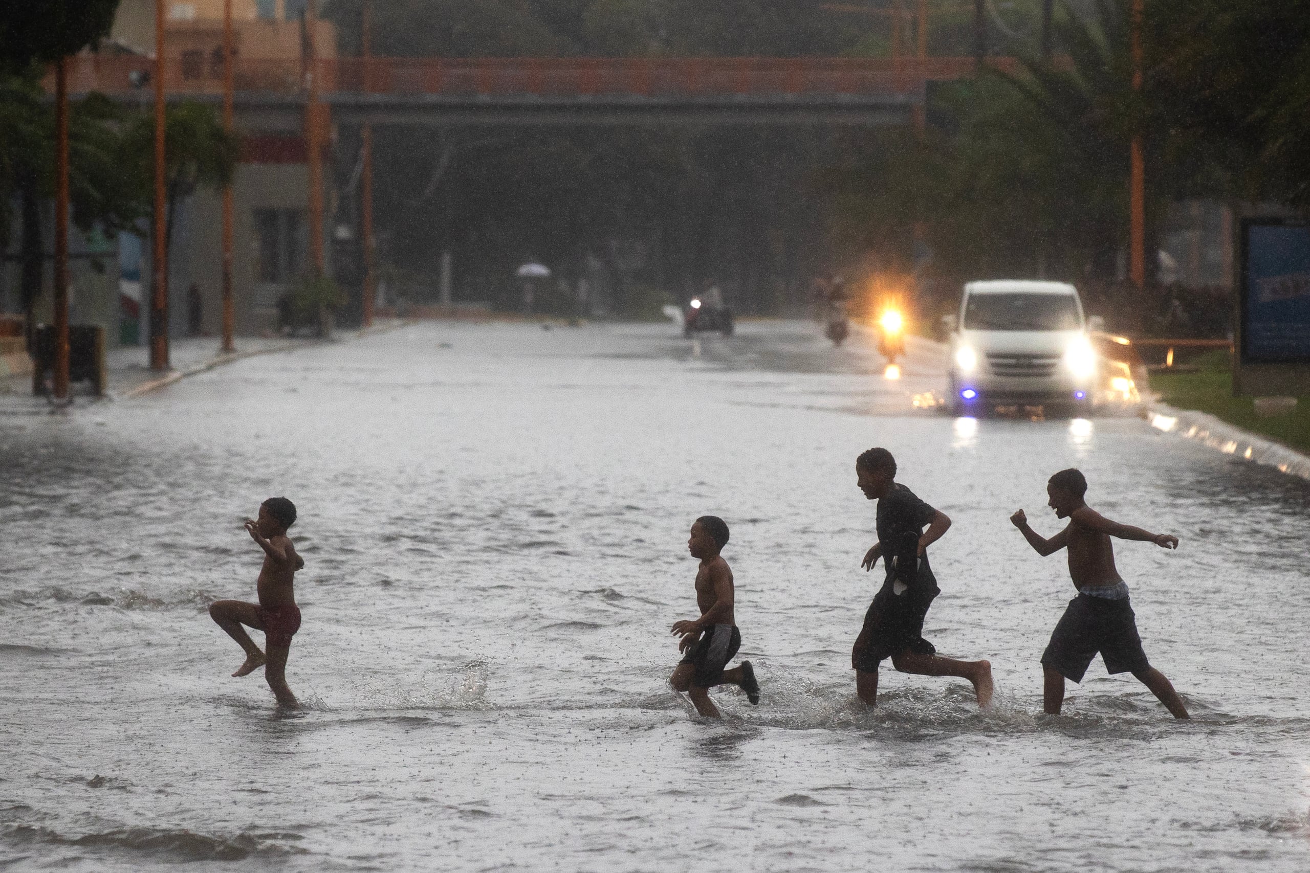Un grupo de niños cruza por una calle inundada en Santo Domingo (República Dominicana). EFE/ Orlando Barría