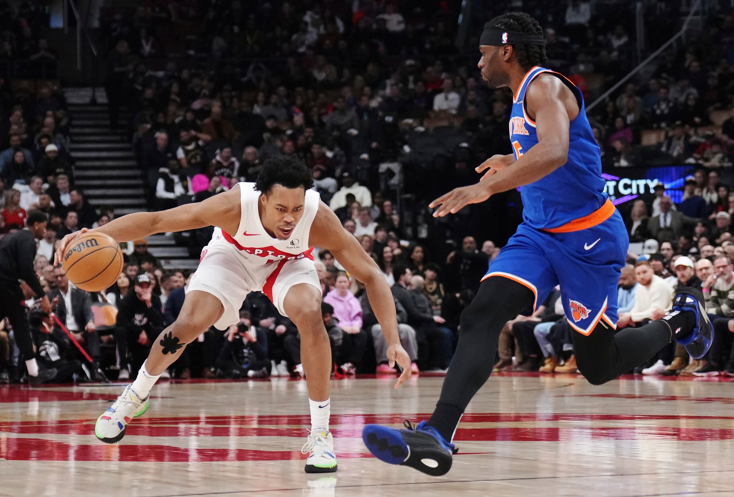 Scottie Barnes de los Raptors de Toronto protege el balón de Precious Achiuwa de los Knicks de Nueva York en el encuentro de la NBA del martes 4 de febrero del 2025.