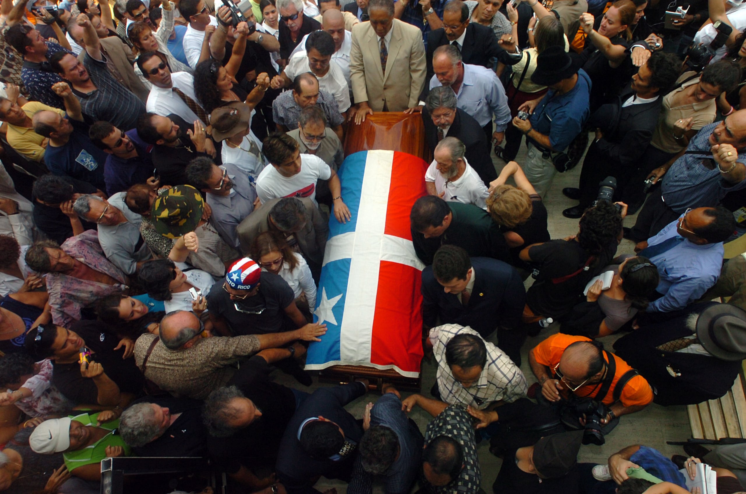 San Juan , Septiembre 26 , 2005 . Los restos del lider de los Macheteros , Filiberto Ojeda Riosfueron trasladados del Ateneo Puertorriquieno al Colegio de Abogados . En la foto el traslado del feretro desde el Ateneo al Colegio de Abogados . Una gran bandera de Lares acompanaba el feretro . En la foto la Ponce De Leon en el area de San Juan . En la foto el feretro llega al Colegio de Abogados .
Foto por : Ramon Tonito Zayas