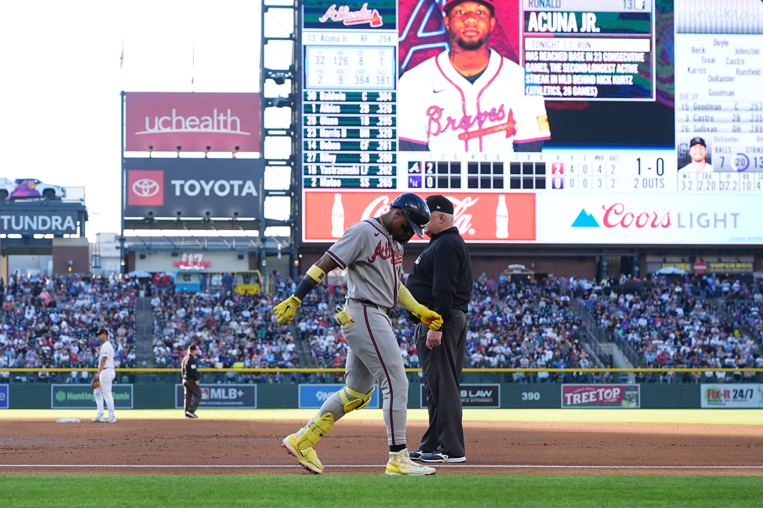 Ronald Acuña Jr. (centro izquierda), de los Braves de Atlanta, camina con dificultad tras lesionarse mientras corría tras un roletazo, mientras el umpire de primera base Bill Miller (centro derecha) observa durante la segunda entrada de un partido de béisbol contra los Rockies de Colorado, el sábado 2 de mayo de 2026, en Denver. (AP Foto/David Zalubowski)