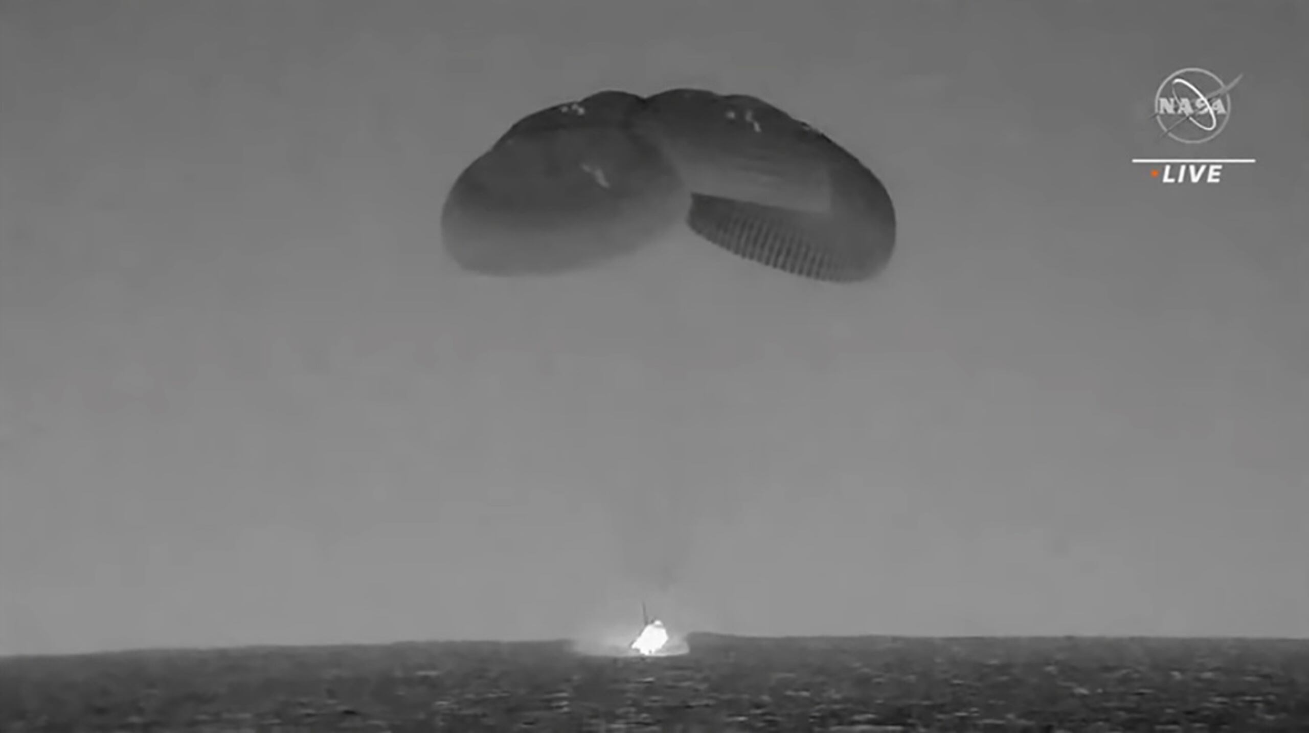 En esta imagen tomada de un video divulgado por la NASA, una cápsula de SpaceX cae en el océano Atlántico este lunes, frente a la costa de Florida.