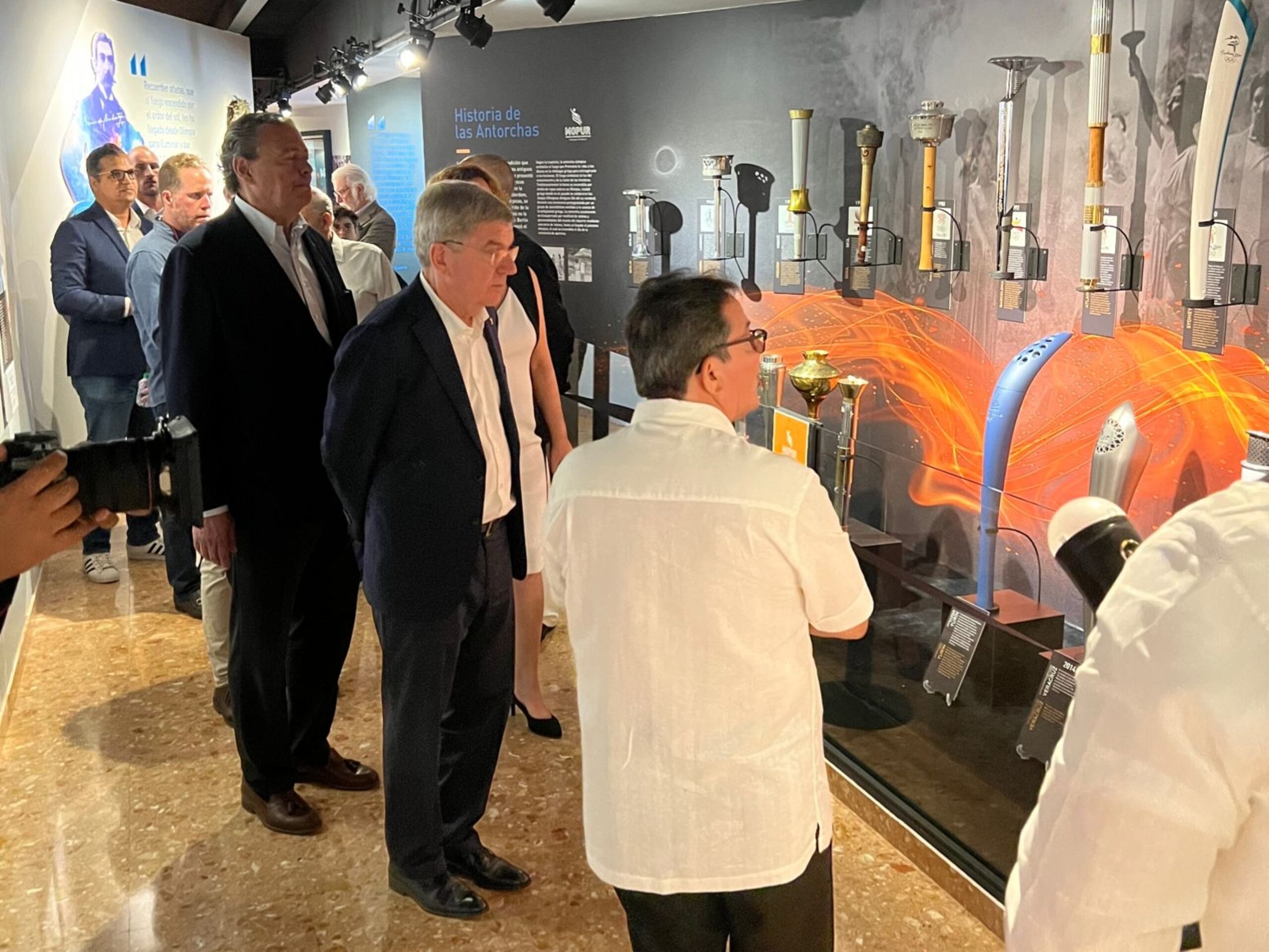 Thomas Bach, al centro de la foto con sus manos en la espalda, visitó el Museo Olímpico de Puerto Rico en su visita a la Isla en el 2021 y observó allí que la colección de antorchas olímpicas estaba incompleta, faltando en específico la de Río 2016, una histórica pues fue la de la primera edición en la que Puerto Rico logró una medalla de oro.