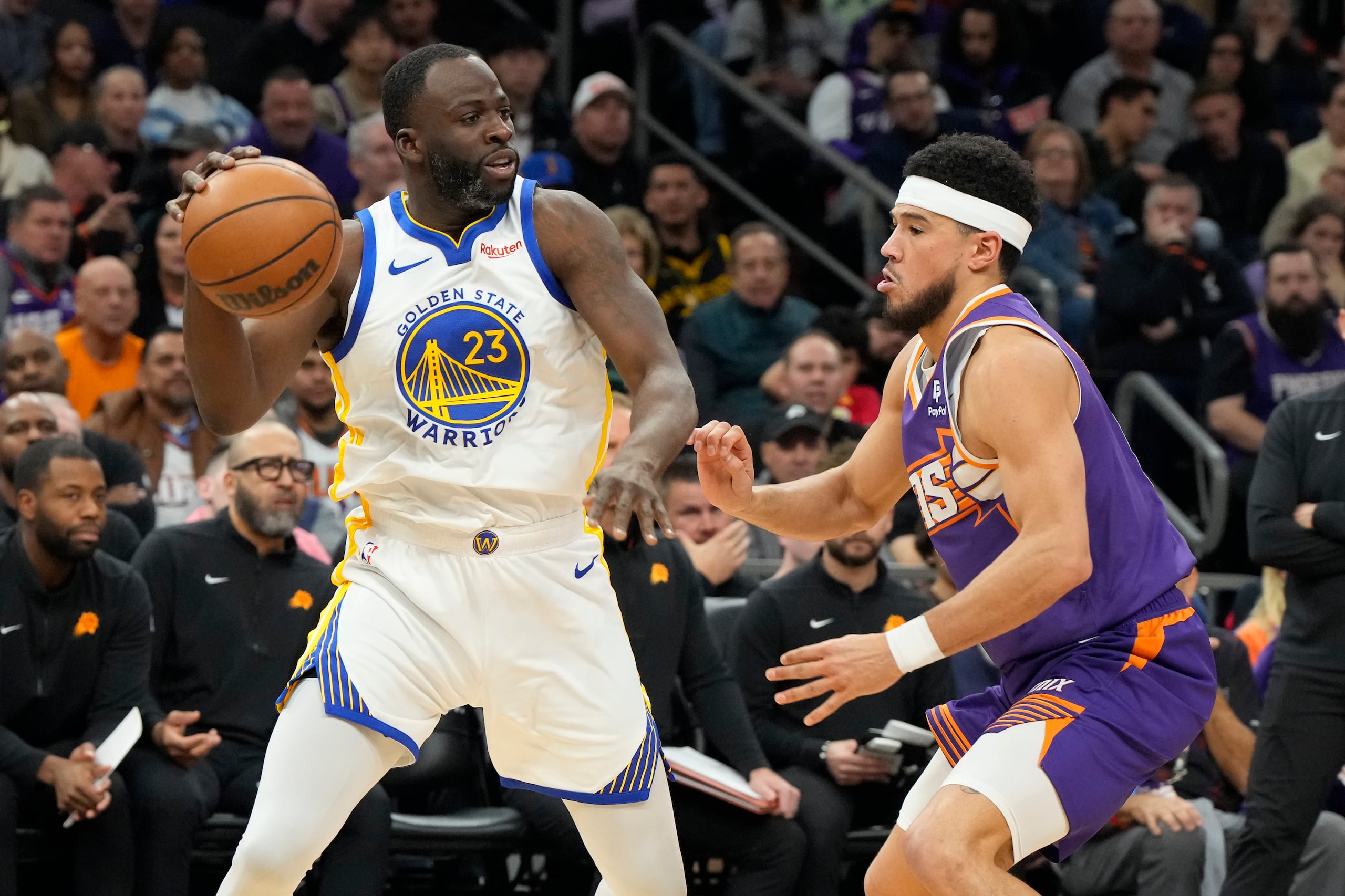 Draymond Green, de los Warriors, es defendido por Devin Booker, de los Suns.