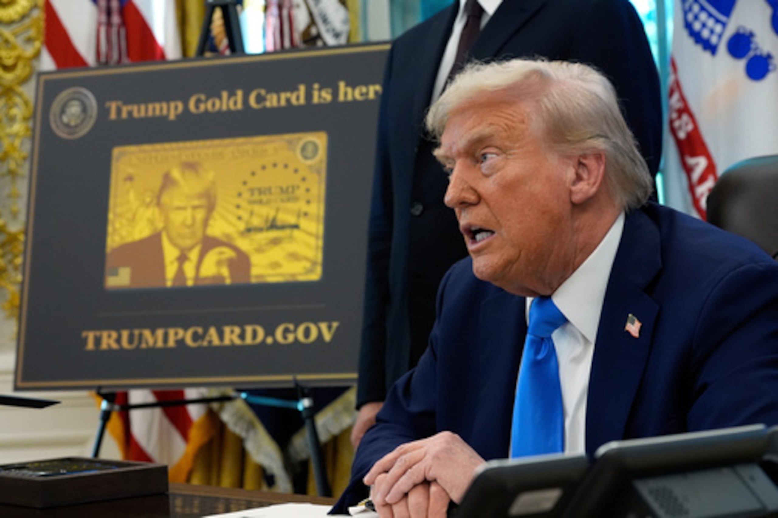 ARCHIVO - Un cartel que muestra la Tarjeta Dorada Trump se ve como el presidente Donald Trump firma órdenes ejecutivas en la Oficina Oval de la Casa Blanca, 19 de septiembre 2025, en Washington. (AP Photo/Alex Brandon, Archivo)