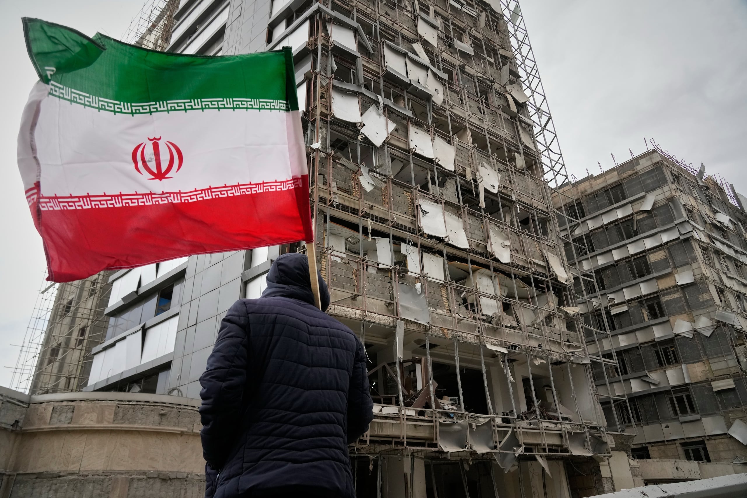 Un hombre sujeta una bandera iraní tras un ataque en Teherán, Irán, el 2 de marzo del 2026. (AP foto/Vahid Salemi)