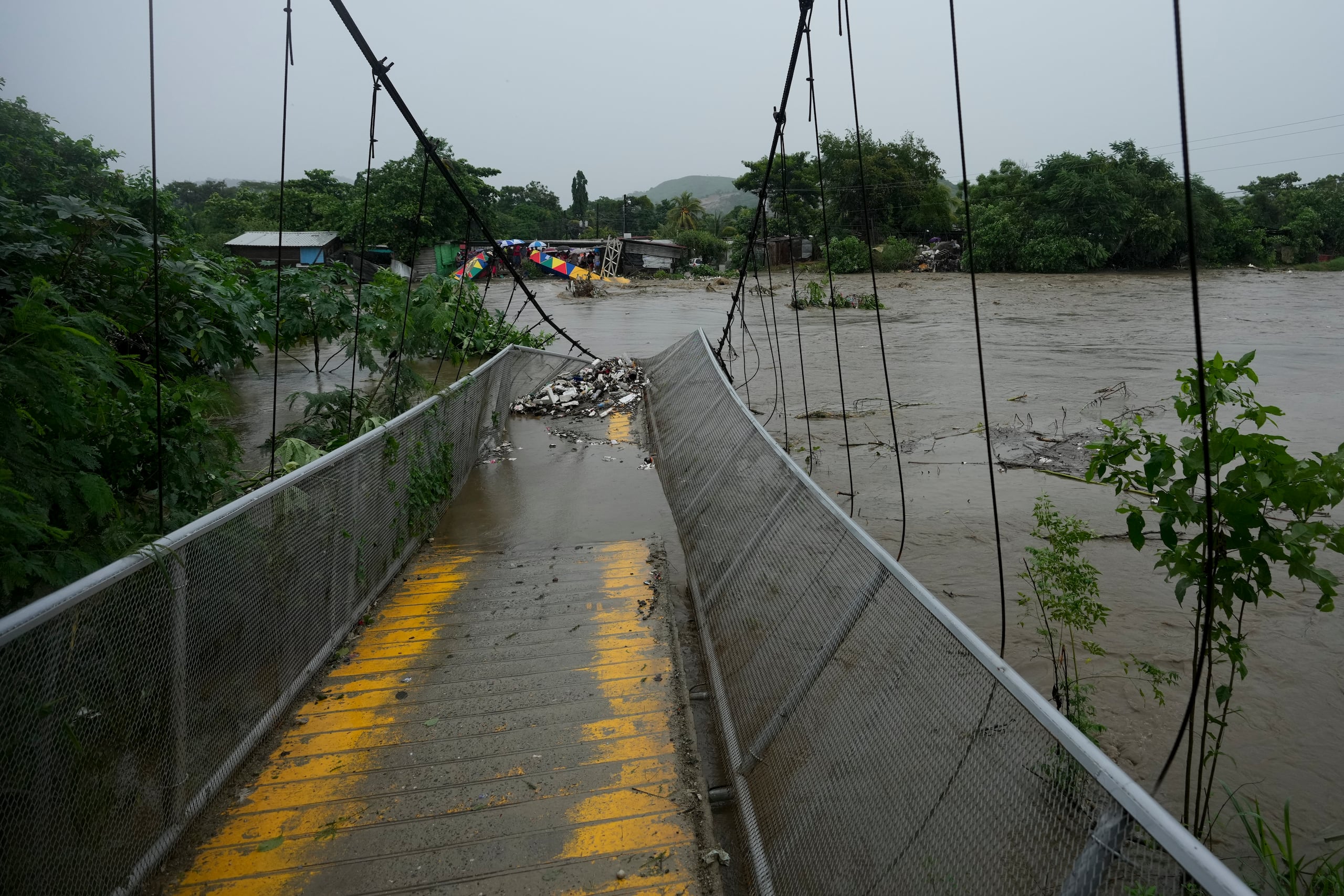 Un puente peatonal colapsado debido a las inundaciones causadas por las lluvias provocadas por la tormenta tropical Sara en San Pedro Sula, Honduras, el sábado 16 de noviembre de 2024. (AP Foto/Moisés Castillo)