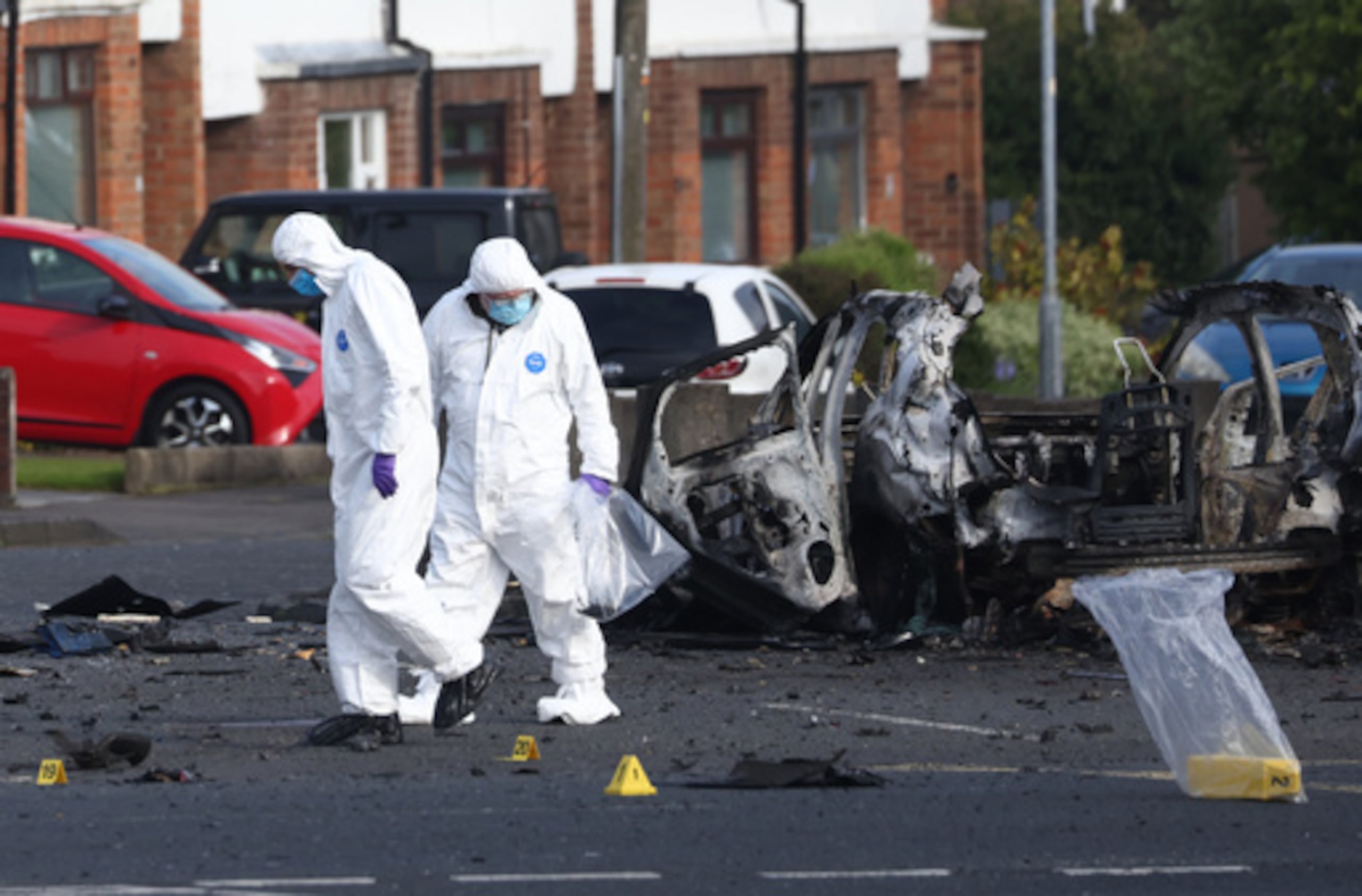 Investigadores forenses inspeccionan el lugar donde explotó un coche bomba frente a la comisaría de Dunmurry, en el sur de Belfast, el domingo 26 de abril de 2026. (AP Photo/Peter Morrison)