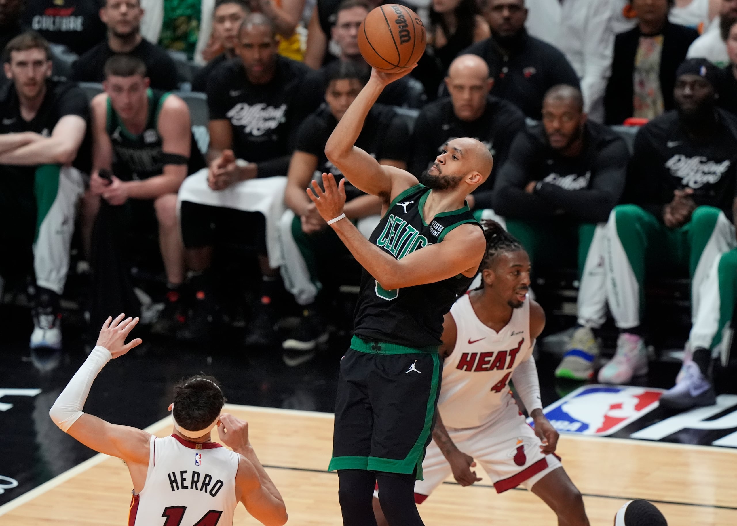 El escolta de los Celtics de Boston, Derrick White (9), anota sobre el escolta del Heat de Miami, Tyler Herro (14), durante la primera mitad del Juego 4 de un partido de primera ronda de baloncesto de la NBA.