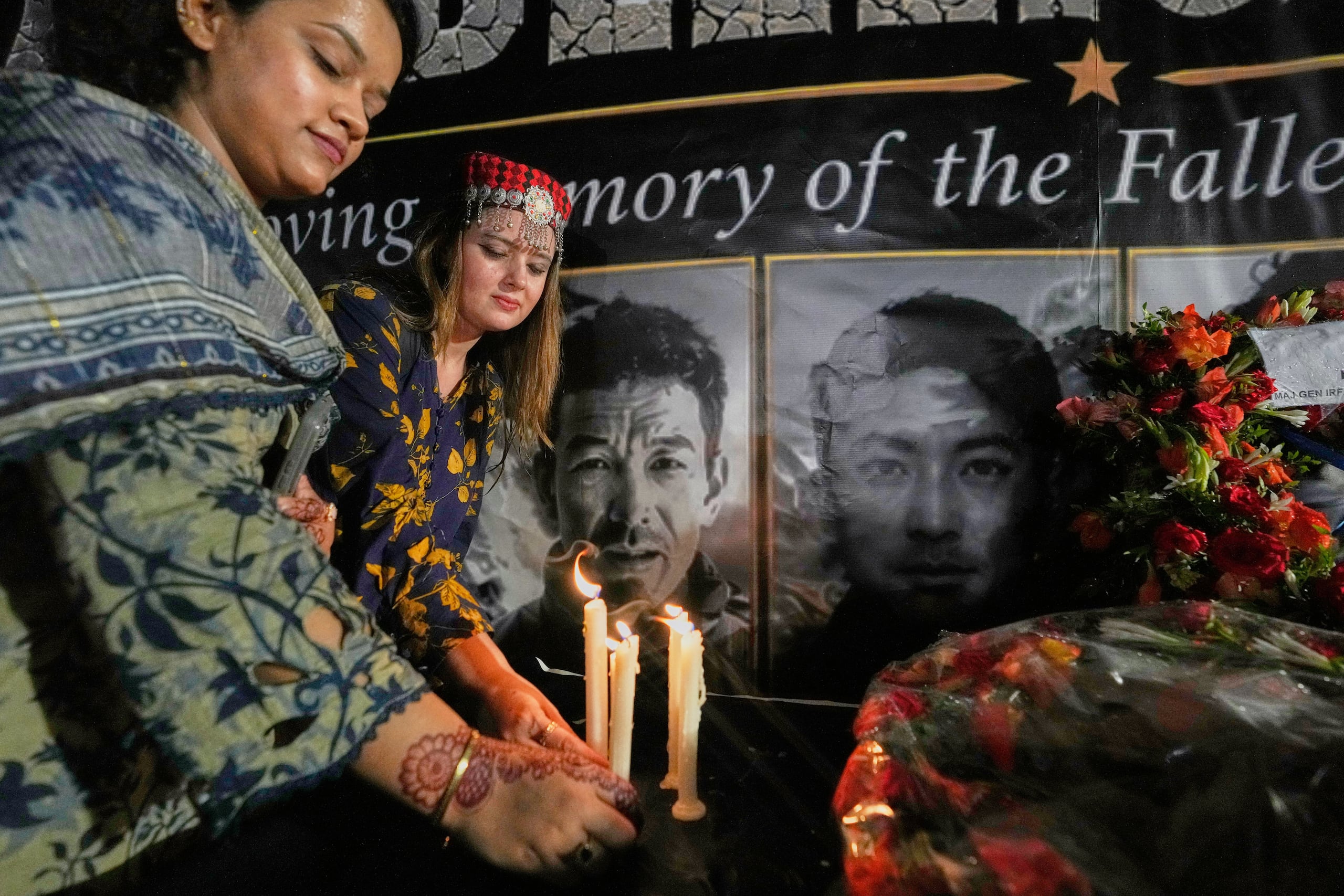 Dos mujeres colocan velas junto a fotografías de los escaladores que perdieron la vida en el Broad Peak, durante una vigilia en su memoria, en Islamabad, Pakistán, el martes 11 de agosto de 2026. (Foto AP/Anjum Naveed)