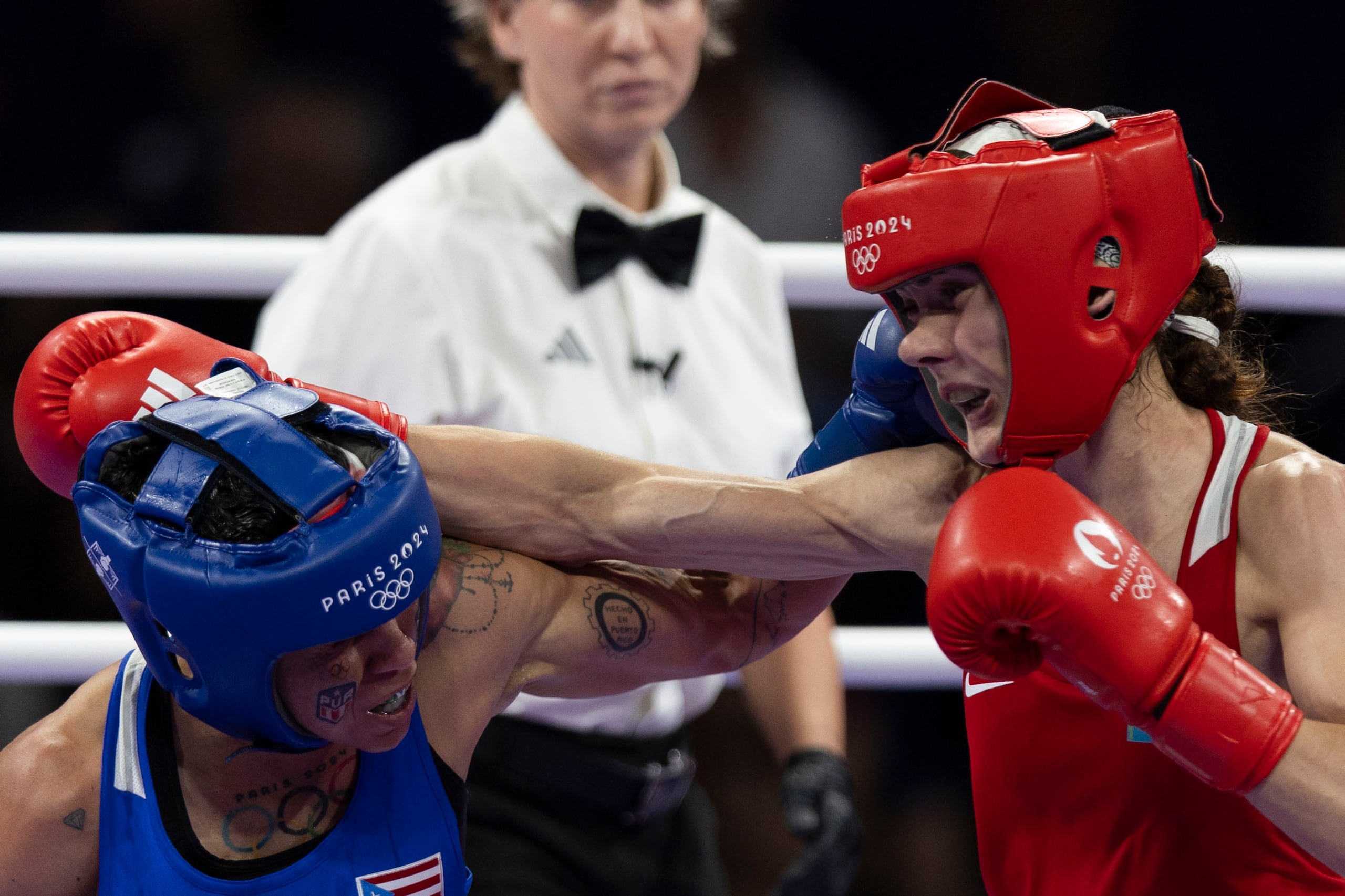 La boxeadora boricua Ashleyann Lozada (azul) conecta una mano al rostro de la kazaja Karina Ibragimova (rojo) en su combate de la ronda de 16 de la división de 57 kilogramos.