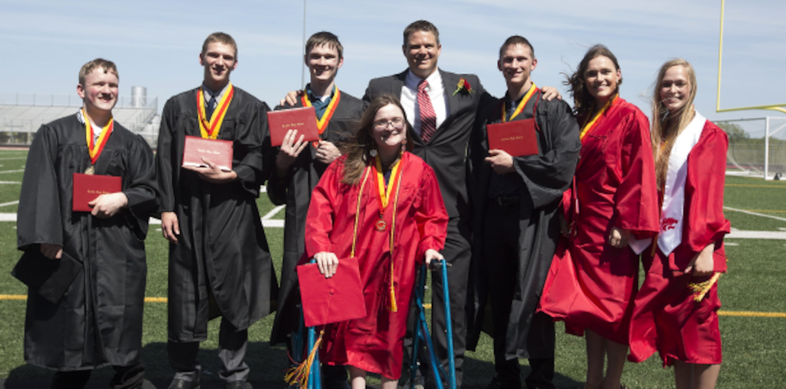 Los septillizos Nathan, Kenny, Joel, Alexis, Brandon, Kelsey y Natalie McCaughey posan para la foto de su graduación junto al director de la escuela secundaria de Carlisle, Matthew Blackstone. (Rachel Mummey/The Des Moines Register via AP)