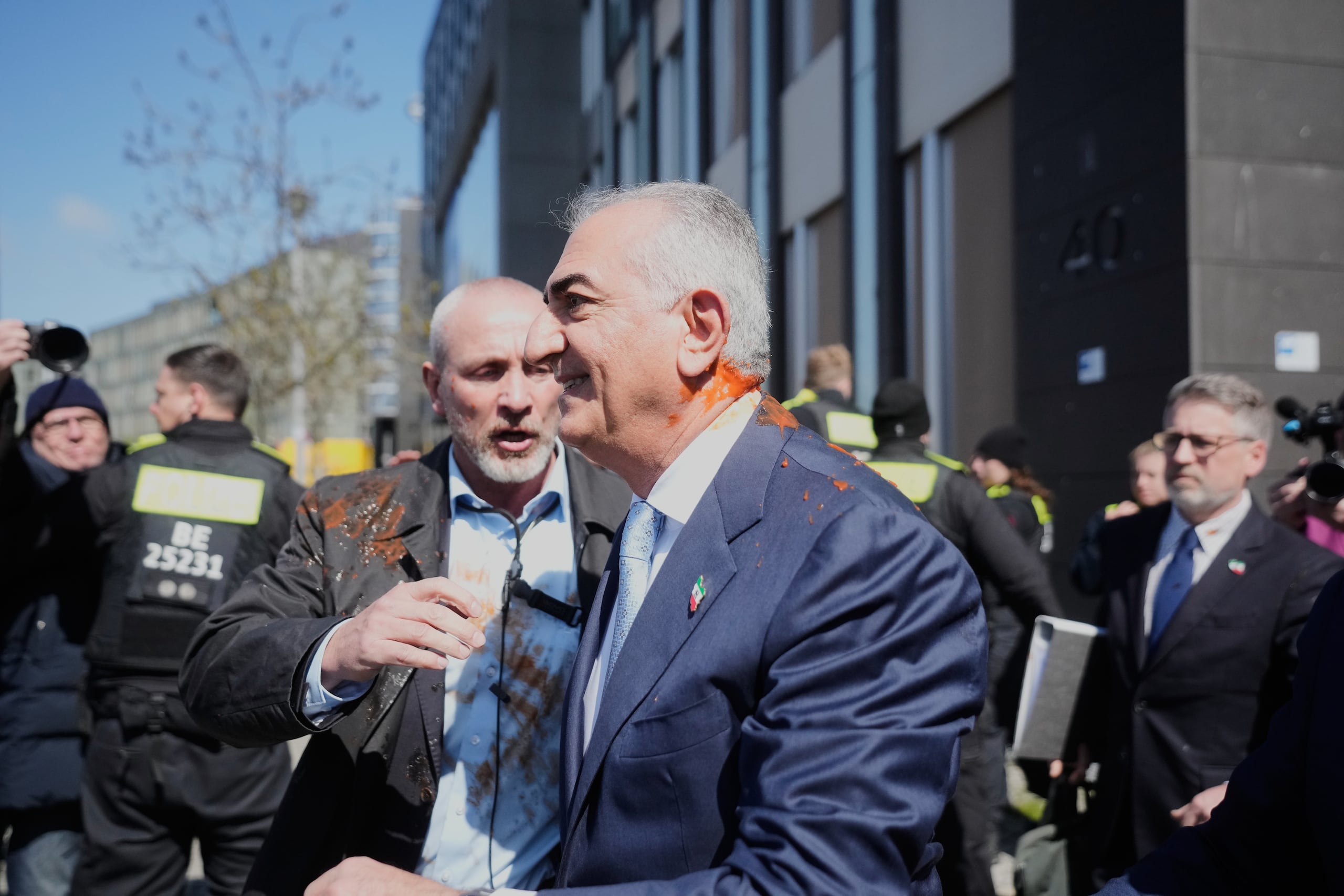 El iraní Reza Pahlavi, hijo exiliado del sha Reza Pahlavi, protegido por fuerzas de seguridad tras ser atacado con un líquido rojo después de una conferencia de prensa en Berlín, Alemania, el jueves
23 de abril de 2026. (AP Foto/Markus Schreiber)