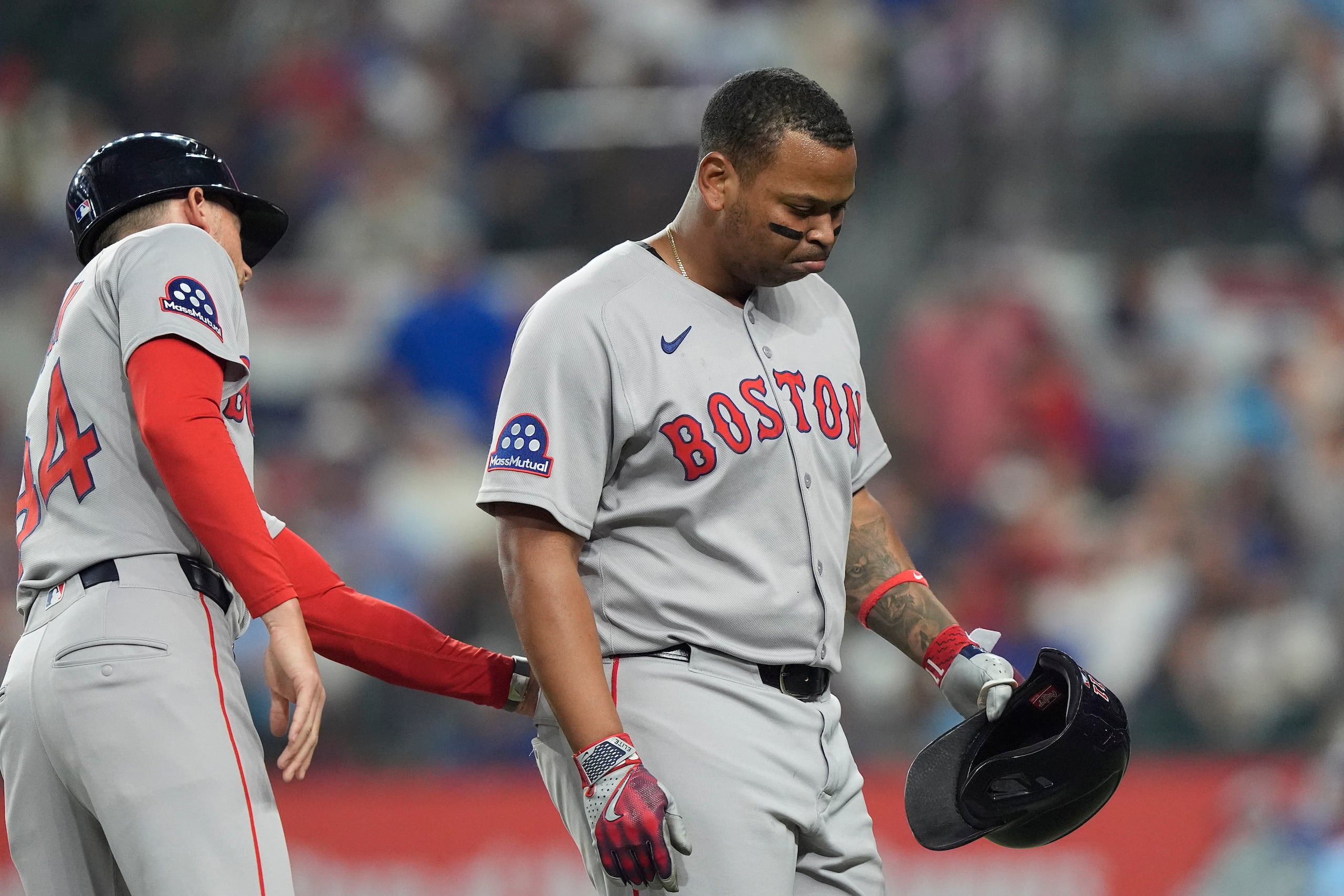 Rafael Devers, derecha, recibe una palmada de ánimo del coach de tercera base Kyle Hudson, izquierda, mientras abandona el campo para darle su lugar a un corredor emergente durante la novena entrada del juego de béisbol de Grandes Ligas frente a los Rangers de Texas, el domingo 30 de marzo de 2025, en Arlington, Texas. (AP Foto/LM Otero)