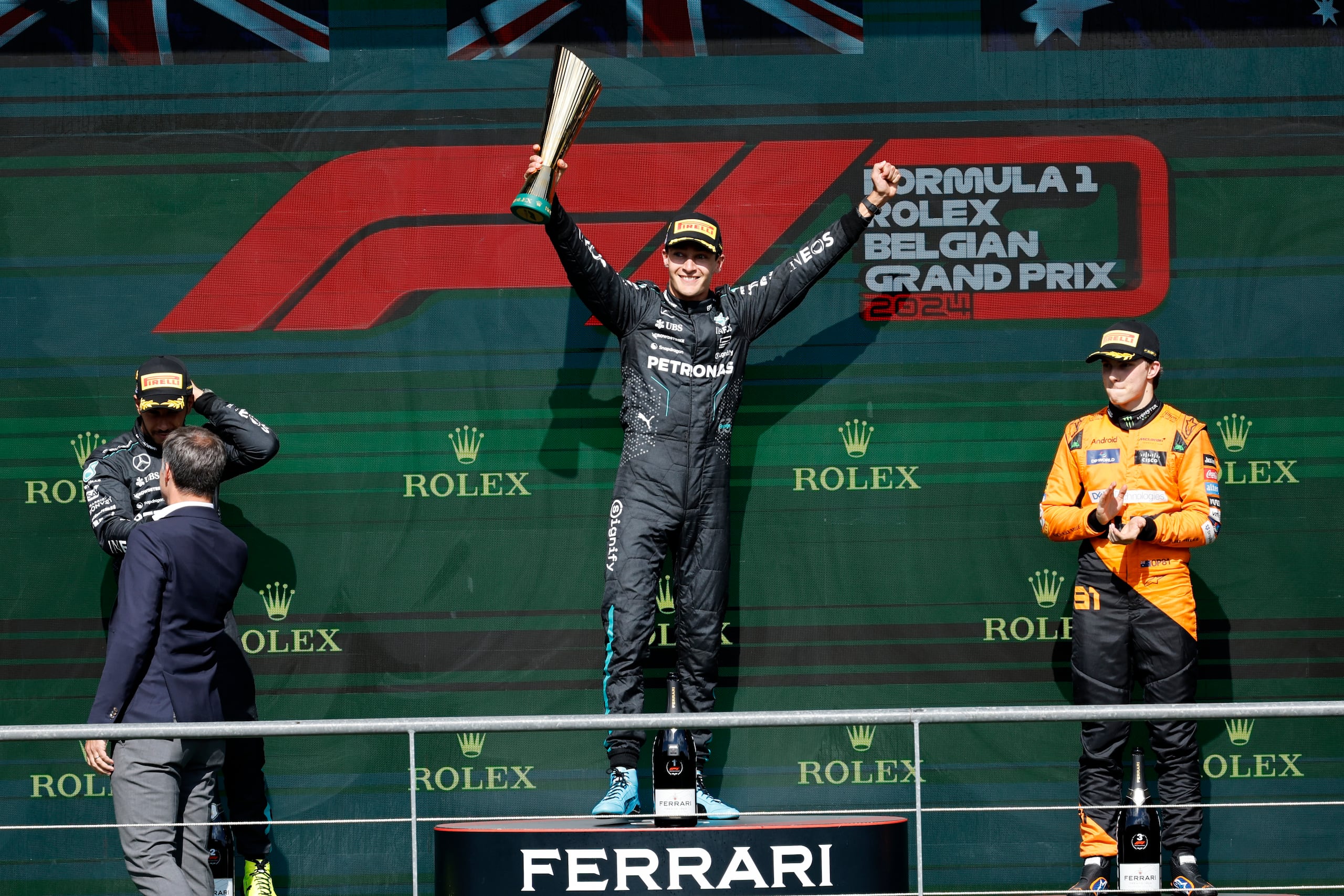 El británico George Russell de Mercedes en el primer lugar, celebra con su compañero Lewis Hamilton, segundo, y Oscar Piastri de McLaren, tercero, en el podio tras el Gran Premio de Bélgica en Spa-Francorchamps el domingo 28 de julio del 2024. (AP Foto/Geert Vanden Wijngaert)